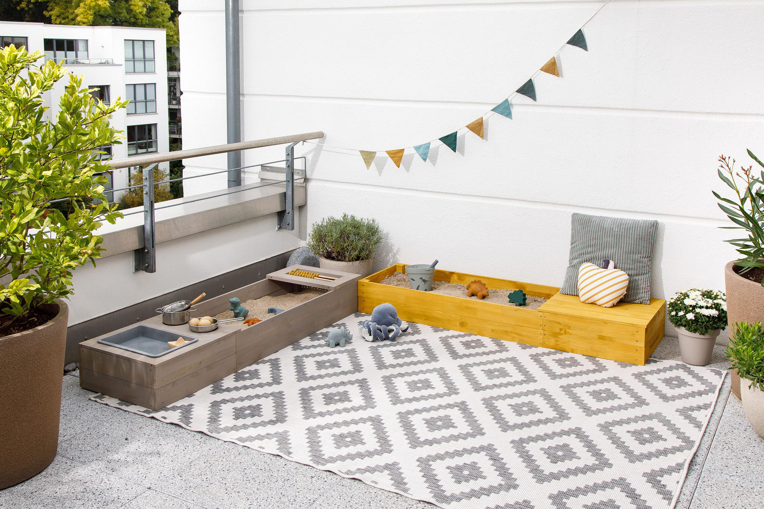 Balkon mit hellgrauen Outdoorteppich mit zwei Sandkästen