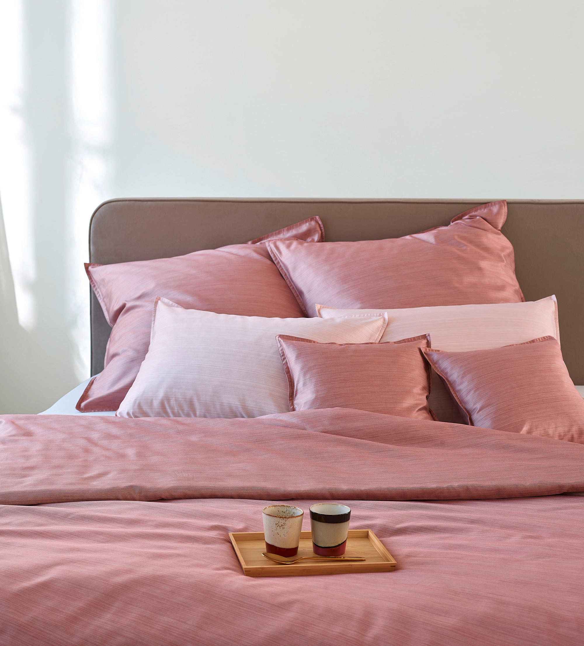 Postelja s rožnatimi rjuhami in blazinami.