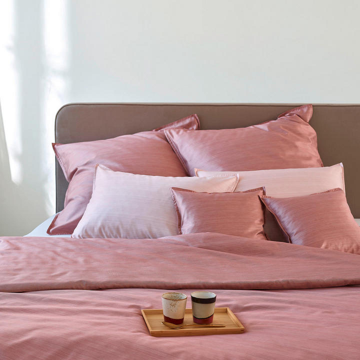 Postelja s rožnatimi rjuhami in blazinami.