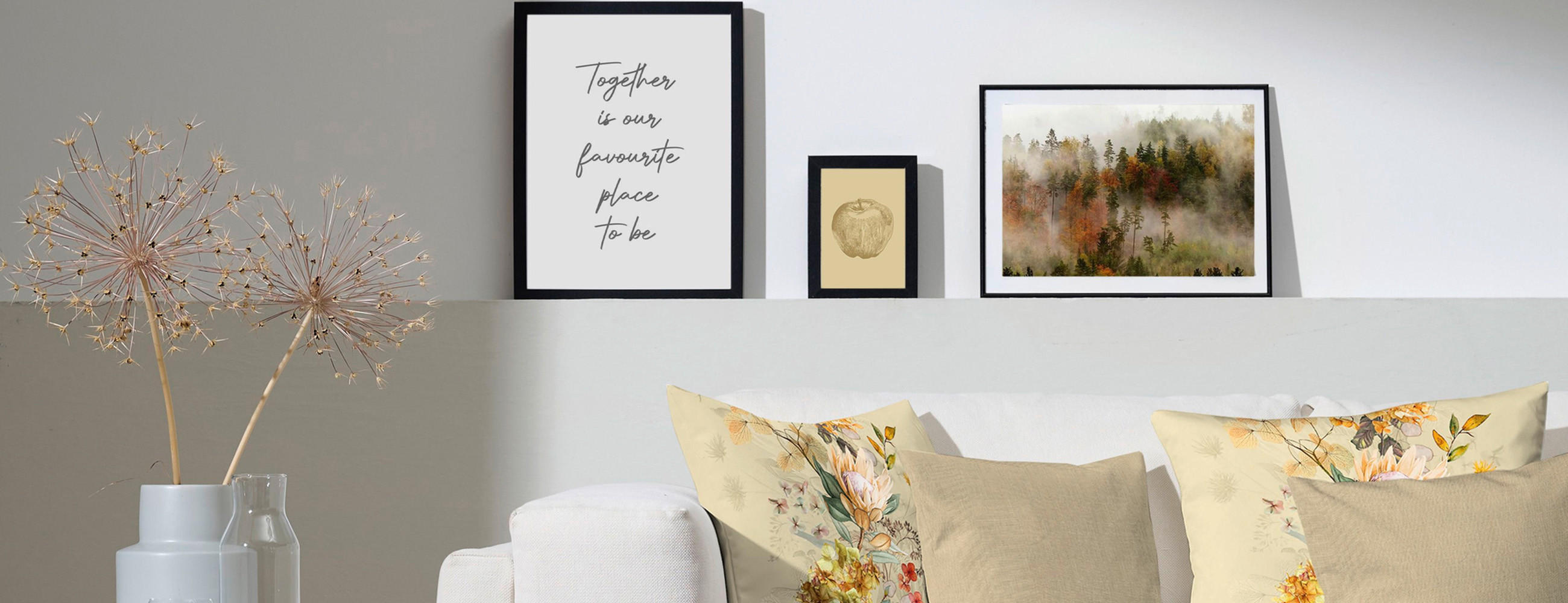 Sofa mit Sofakissen und darüber gerahmte Bilder