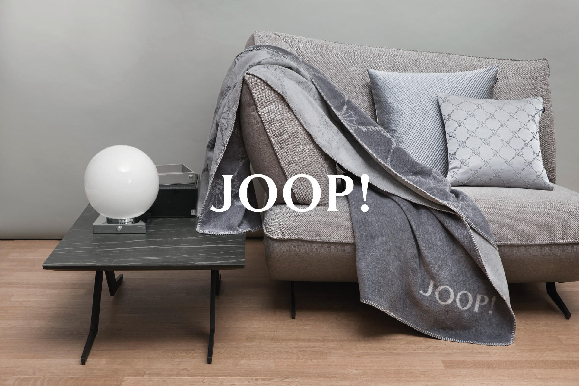 Šedá deka Joop na šedé sedačce