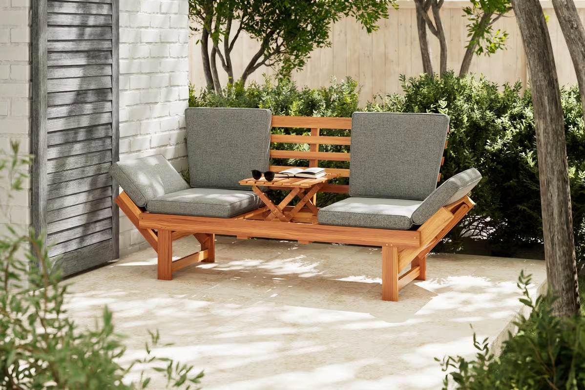 Braune Holzbank mit grauen Stoffauflagen auf einer Terrasse