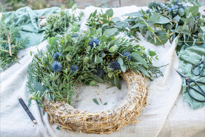 Ein dekorativer Kranz aus Blättern und Pflanzen auf einem Tisch, der für eine frische und lebendige Stimmung sorgt.
