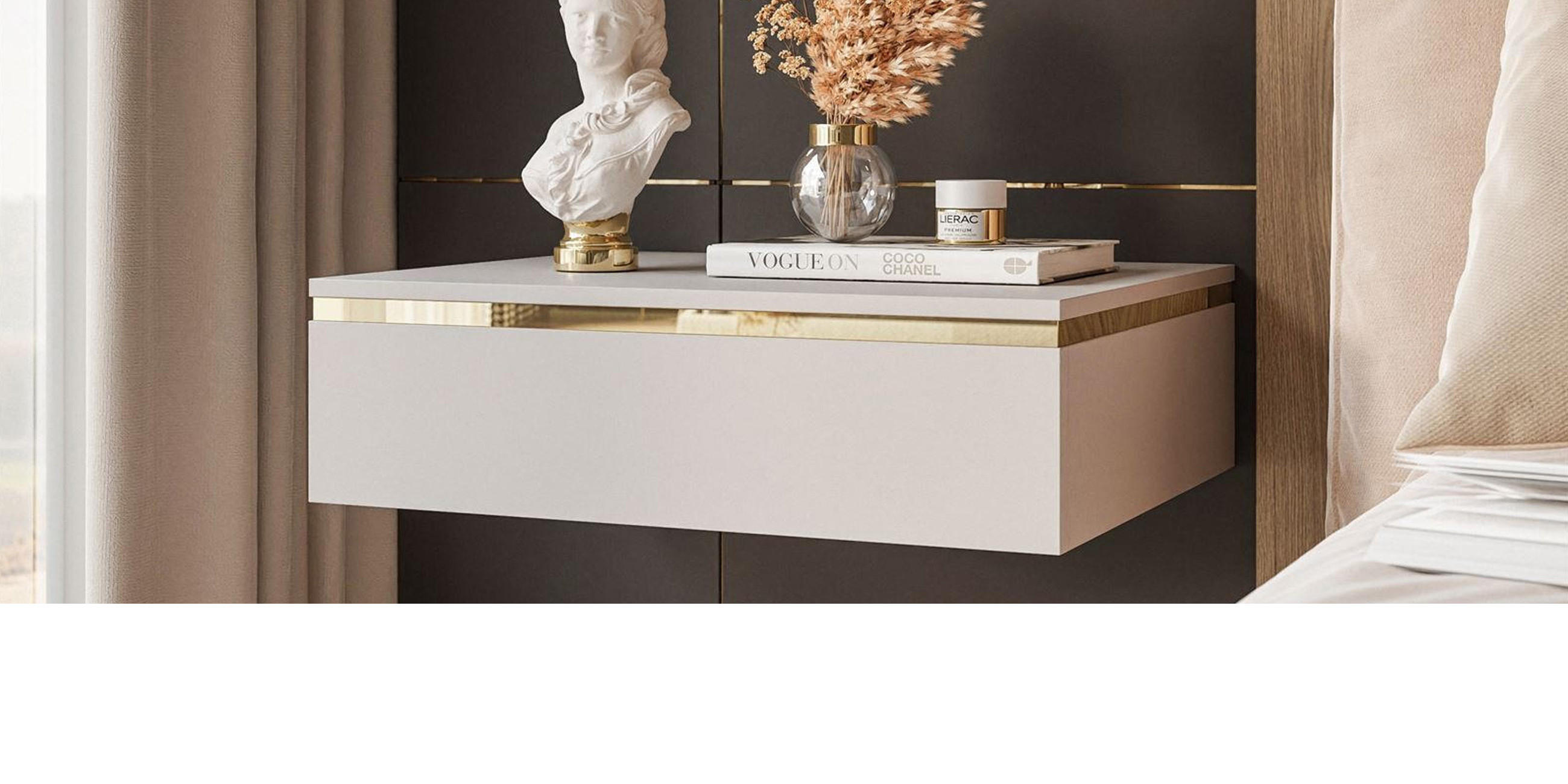 Freihängender Nachttisch in beige mit goldenem Akzent und Dekoration vor grauer Wand.