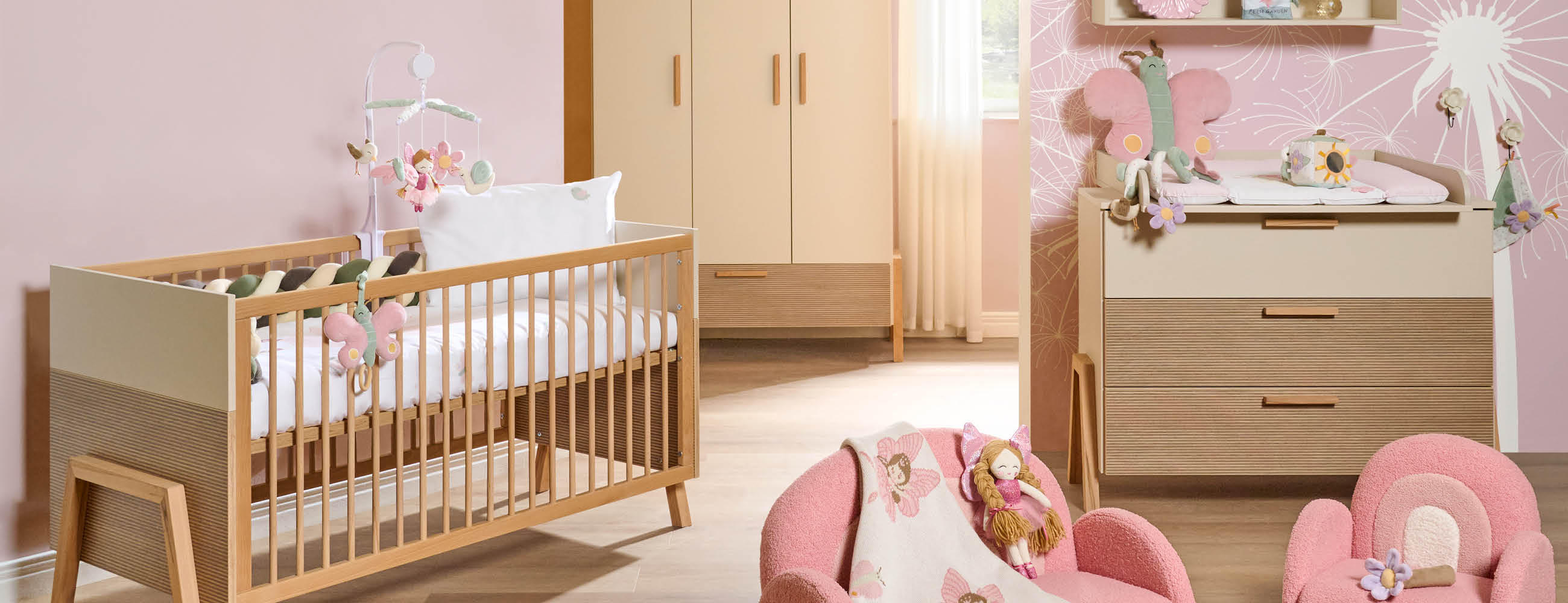 Ein helles Babyzimmer mit rosa Wänden und Möbeln, das eine gemütliche Umgebung für das Baby bietet.