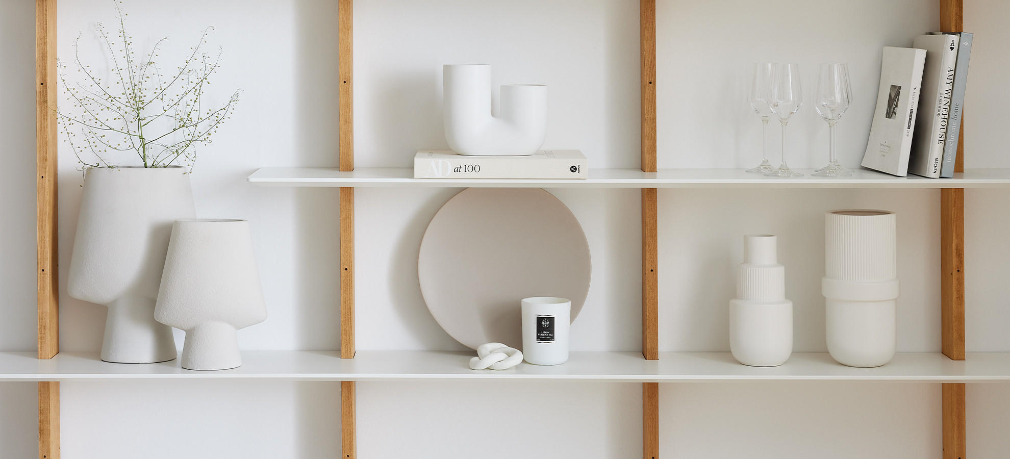 Minimalistische Regaldekoration mit weißen Vasen, Büchern und Gläsern, begleitet vom Text „Trends & Wohnideen – Jetzt inspirieren lassen“