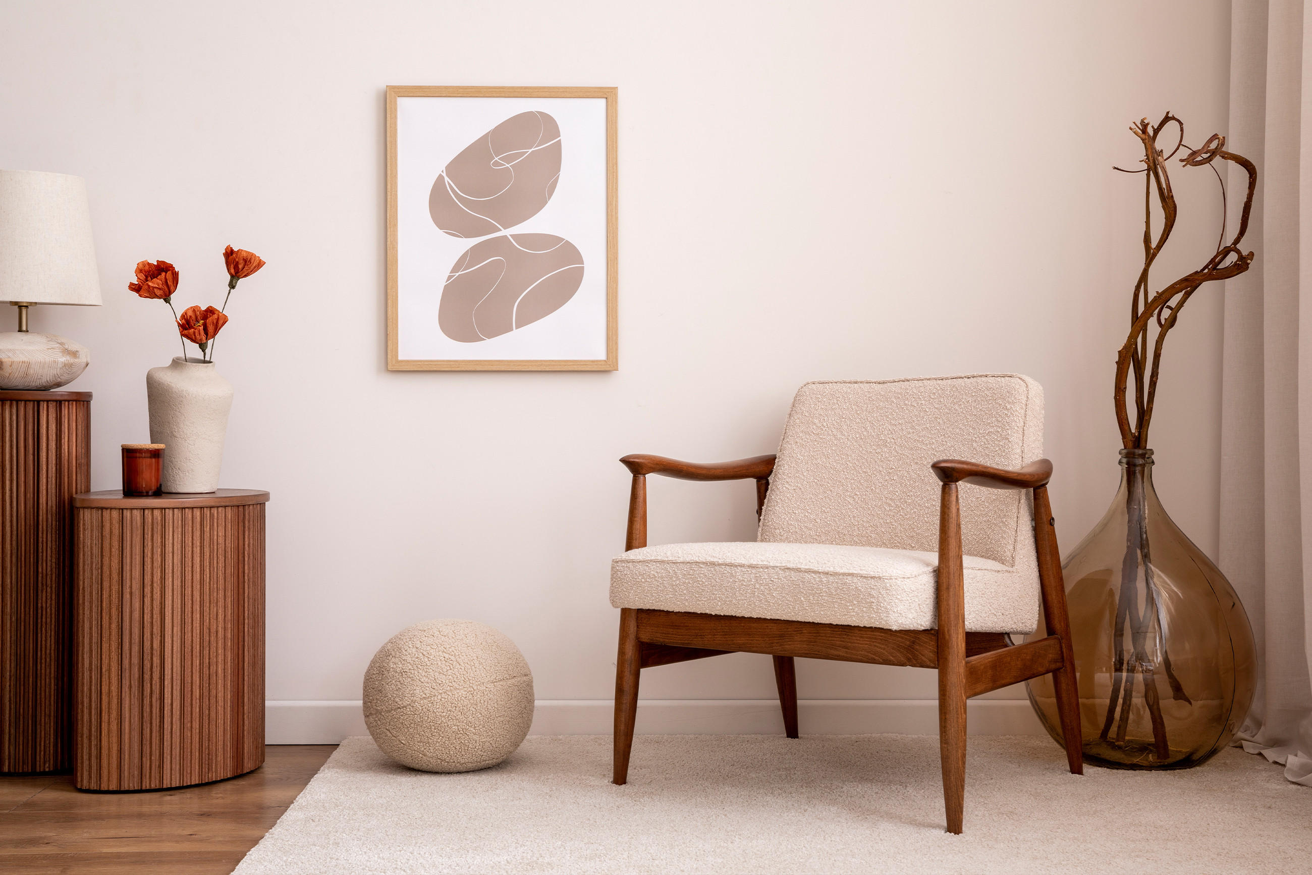 Gemütliche Wohnszene im Cocooning-Stil mit beigem Sessel, geriffeltem Holztisch, warmen Naturtönen und dekorativen Elementen wie Trockenblumen und abstrakter Wandkunst – ideal für entspannte Rückzugsorte.