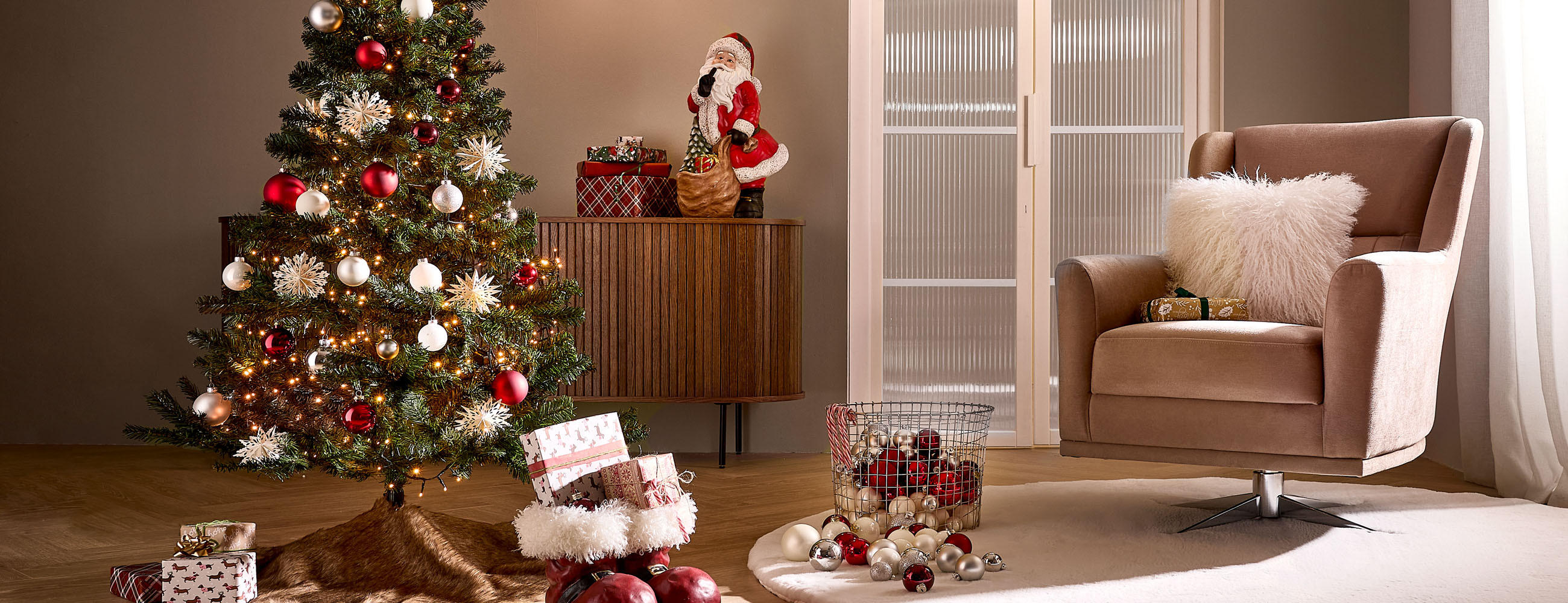 Weihnachtlich dekoriertes Wohnzimmer mit beleuchtetem Baum, Geschenken und gemütlichem Sessel.