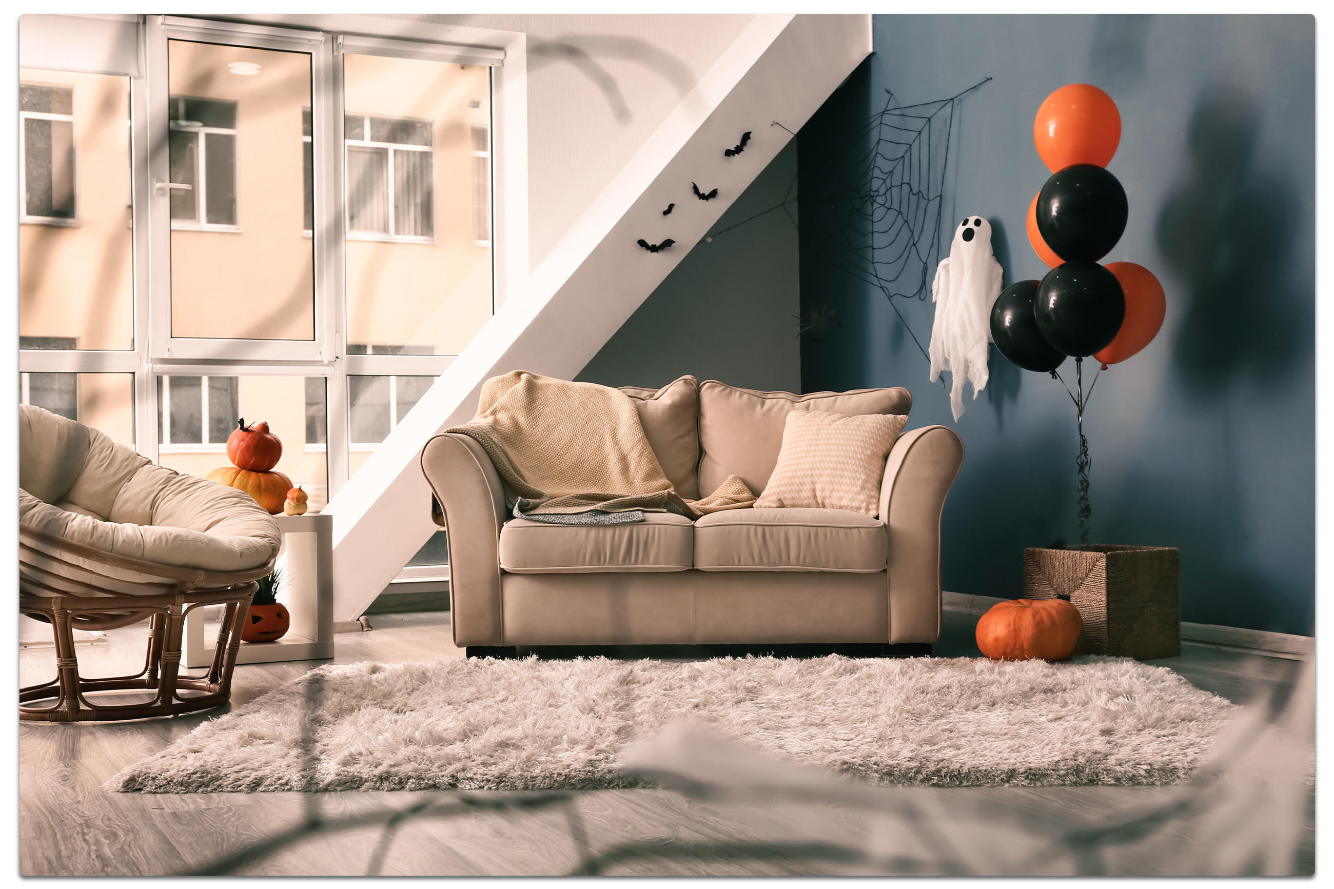 Gemütliches Wohnzimmer mit Sofa, Sessel und einer Kürbisdekoration für Halloween.