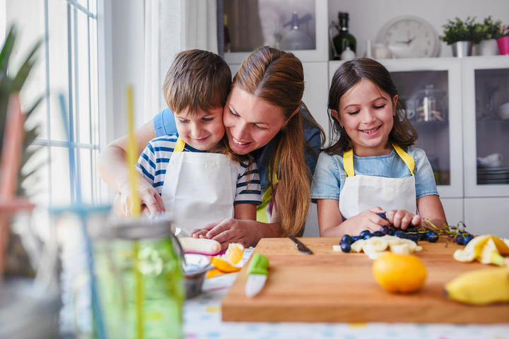 Frau kocht mit Kindern in der Küche
