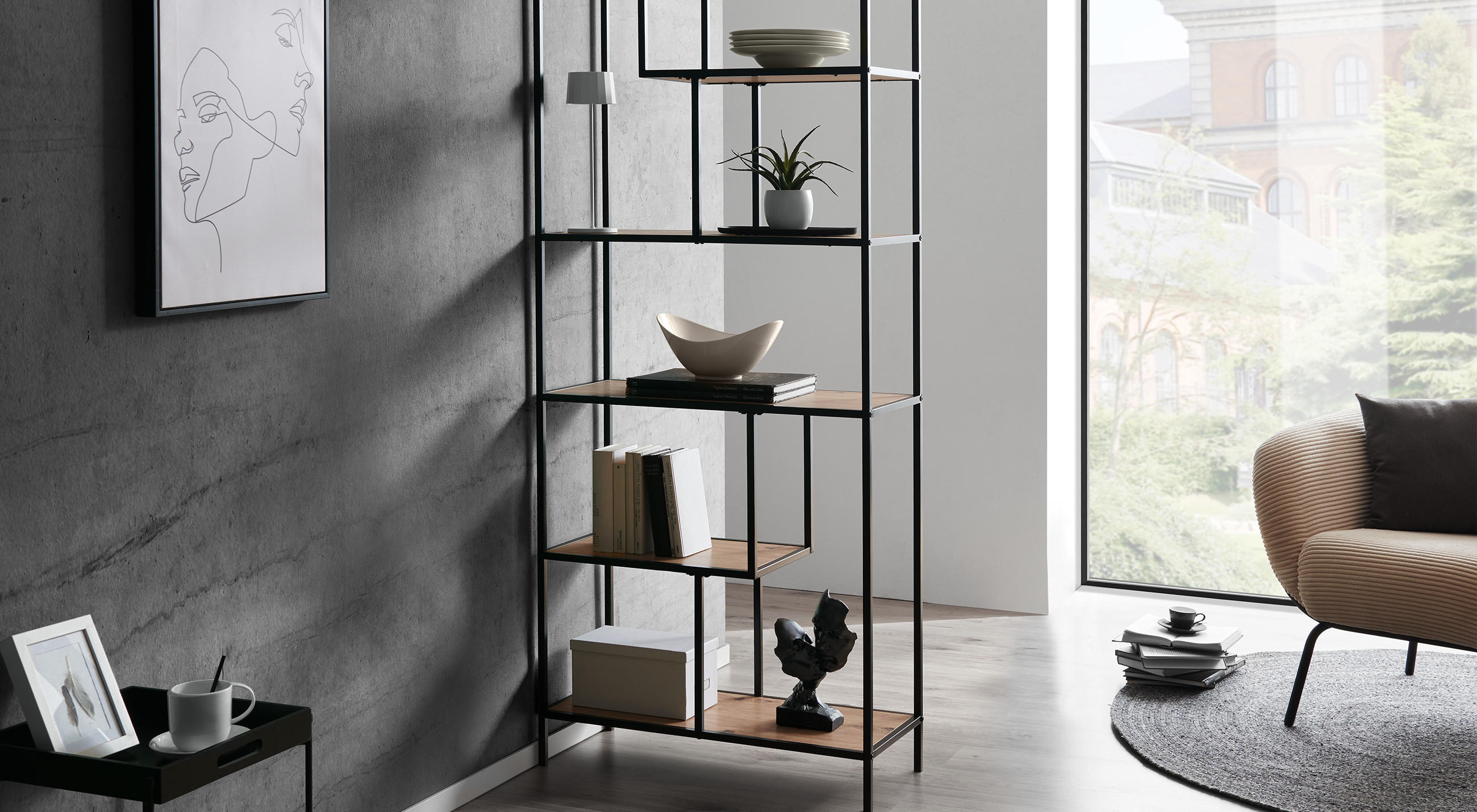 Offenes Regal mit schwarzem Metallgestell und Holzfachböden, dekoriert mit Büchern, weißer Schale, einer kleinen Pflanze und Kunstobjekten; links Wand mit minimalistischer Linienzeichnung, rechts cremefarbener Bouclé‑Sessel und großes Fenster.