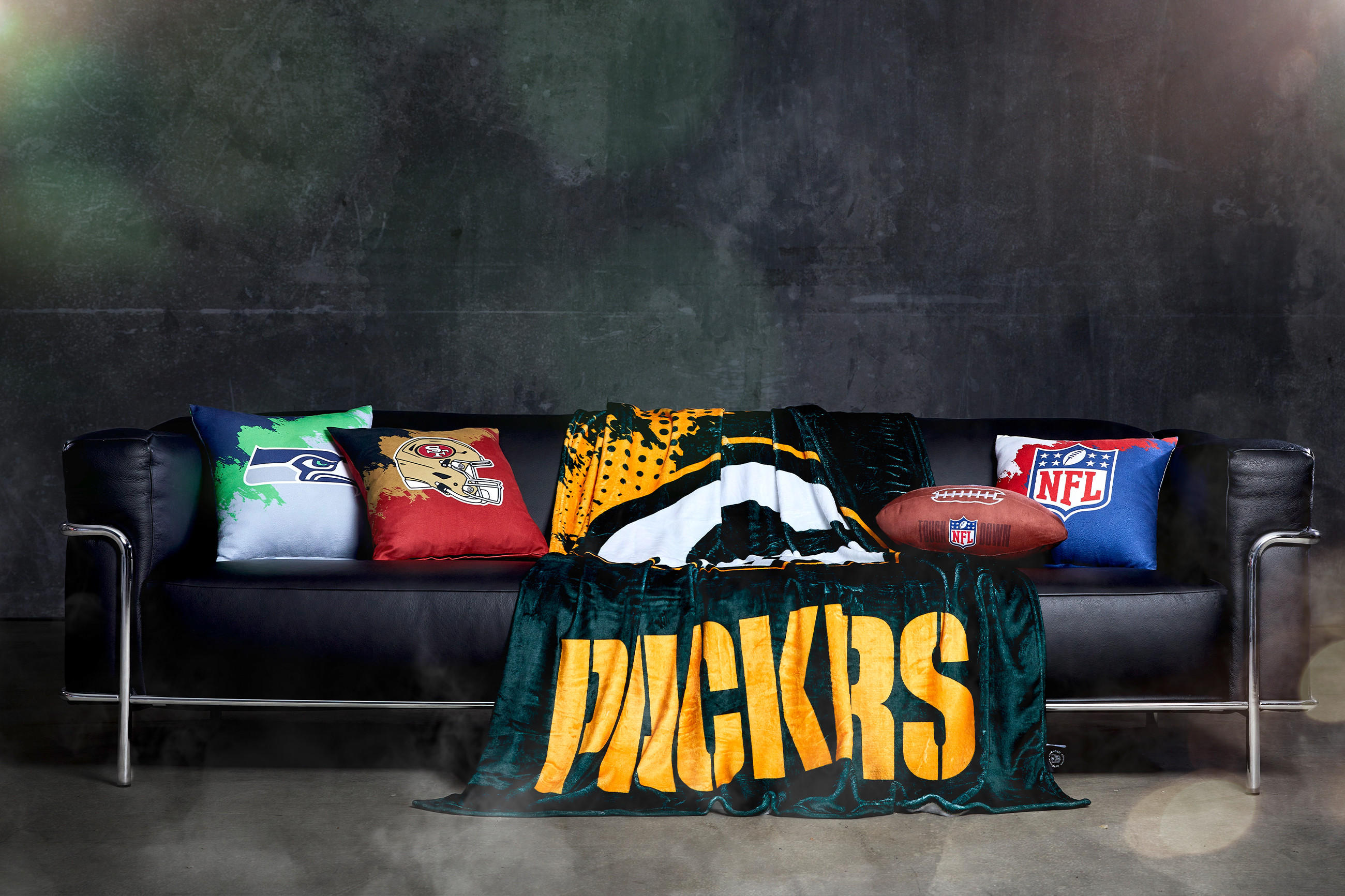 Gemütliche Couch mit einer Decke und einem Fußball, ideal für den Super Bowl.