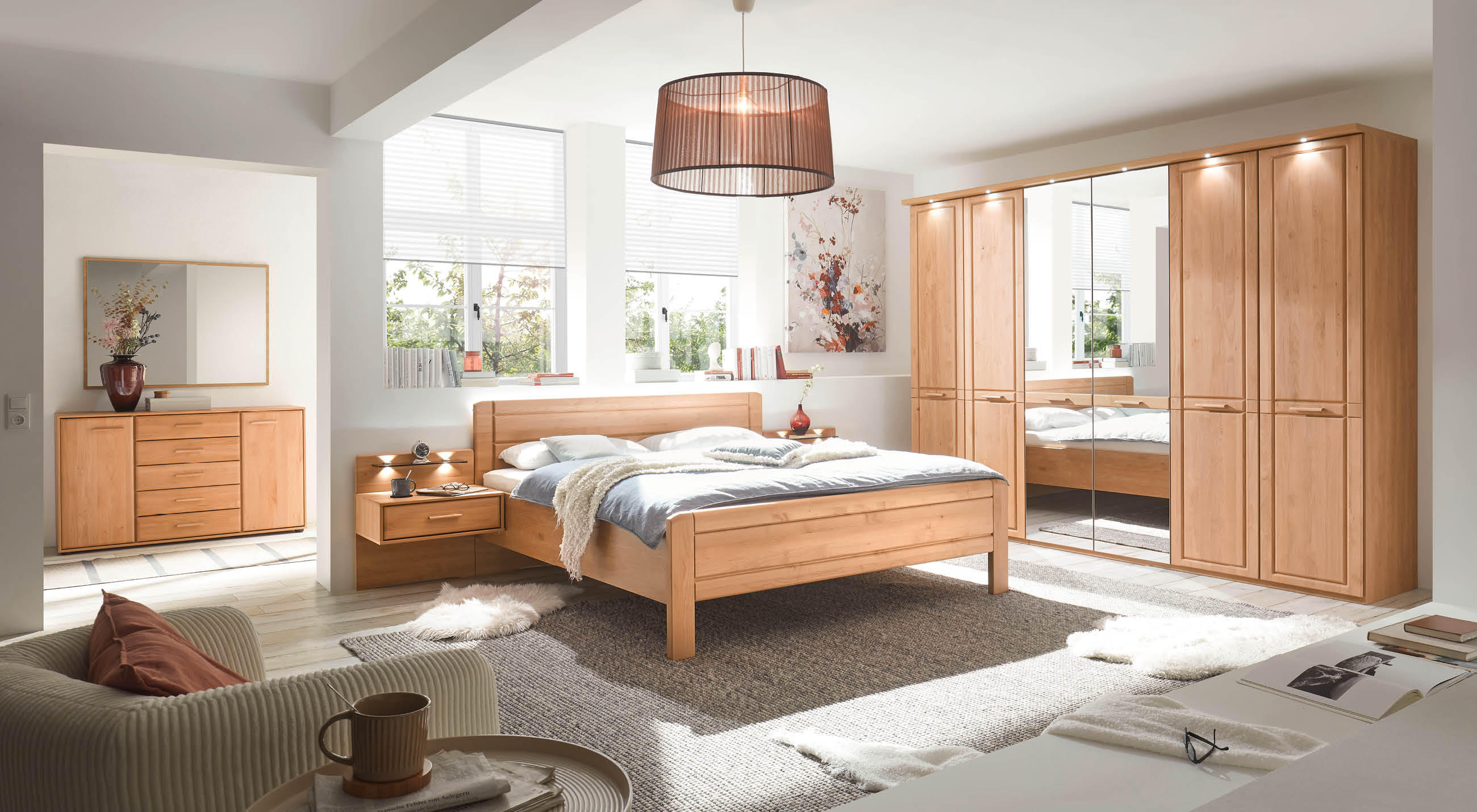 Schlafzimmeransicht mit Bett, Kommode und einem Kleiderschrank aus Holz mit einem Spiegel.