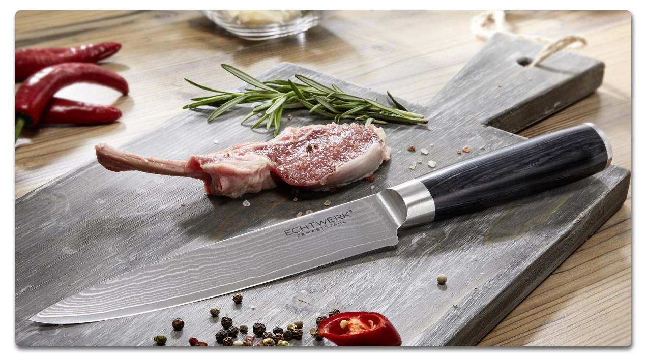 scharfes Messer auf einem schwarzen Brett mit Fleisch