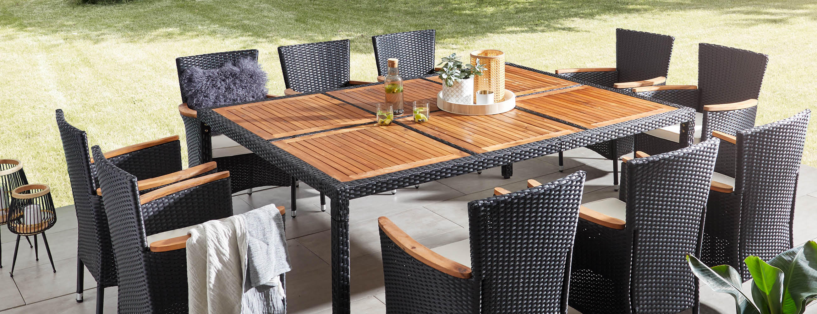 Ein eleganter, rechteckiger Holztisch mit Schwarzer Umrandung mit Stühlen in den Farben anthrazit, steht im Freien