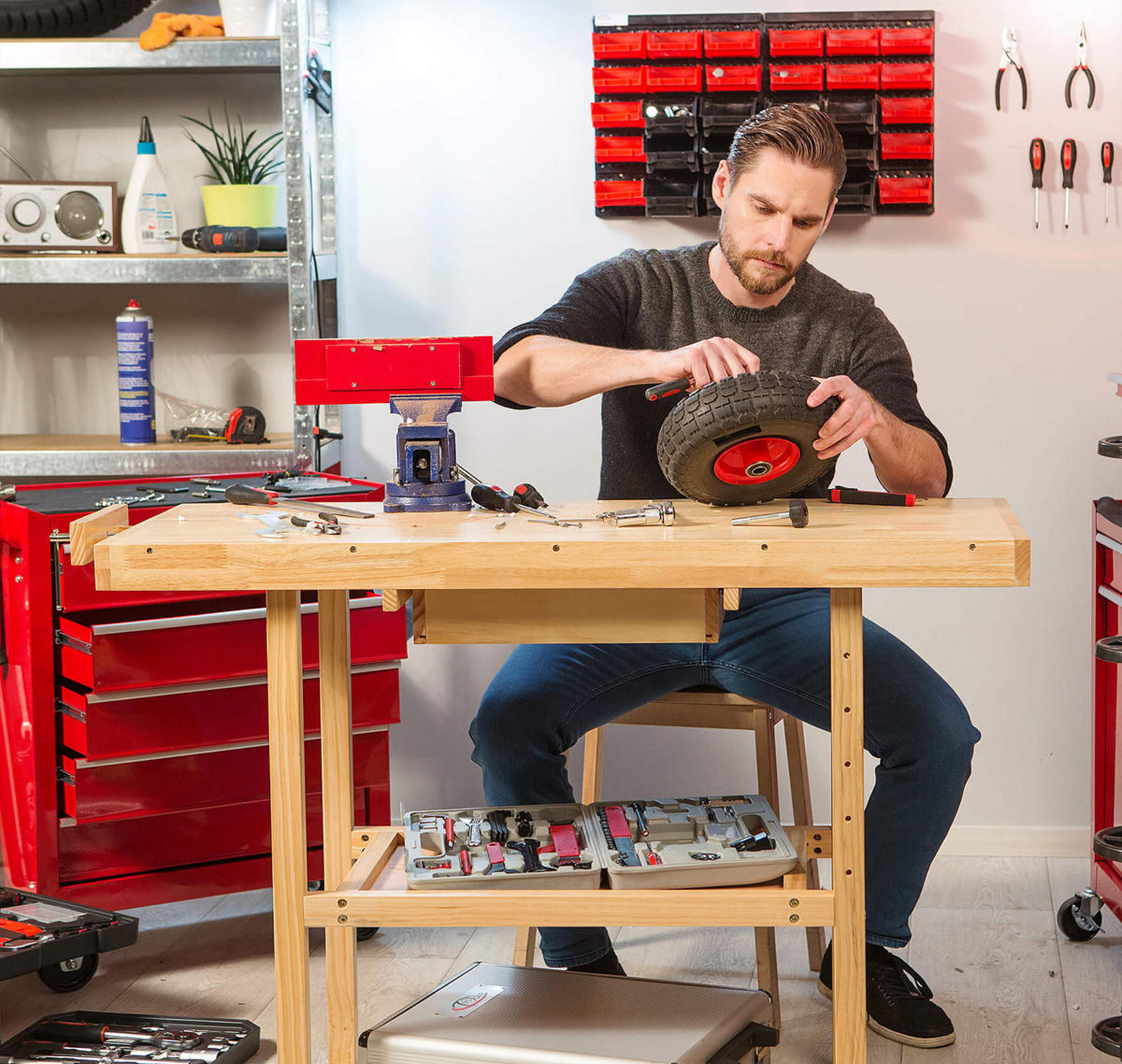 Ein Mann arbeitet an einem Rad in einer Werkstatt, umgeben von Werkzeugen und Materialien für Heimwerkerprojekte.