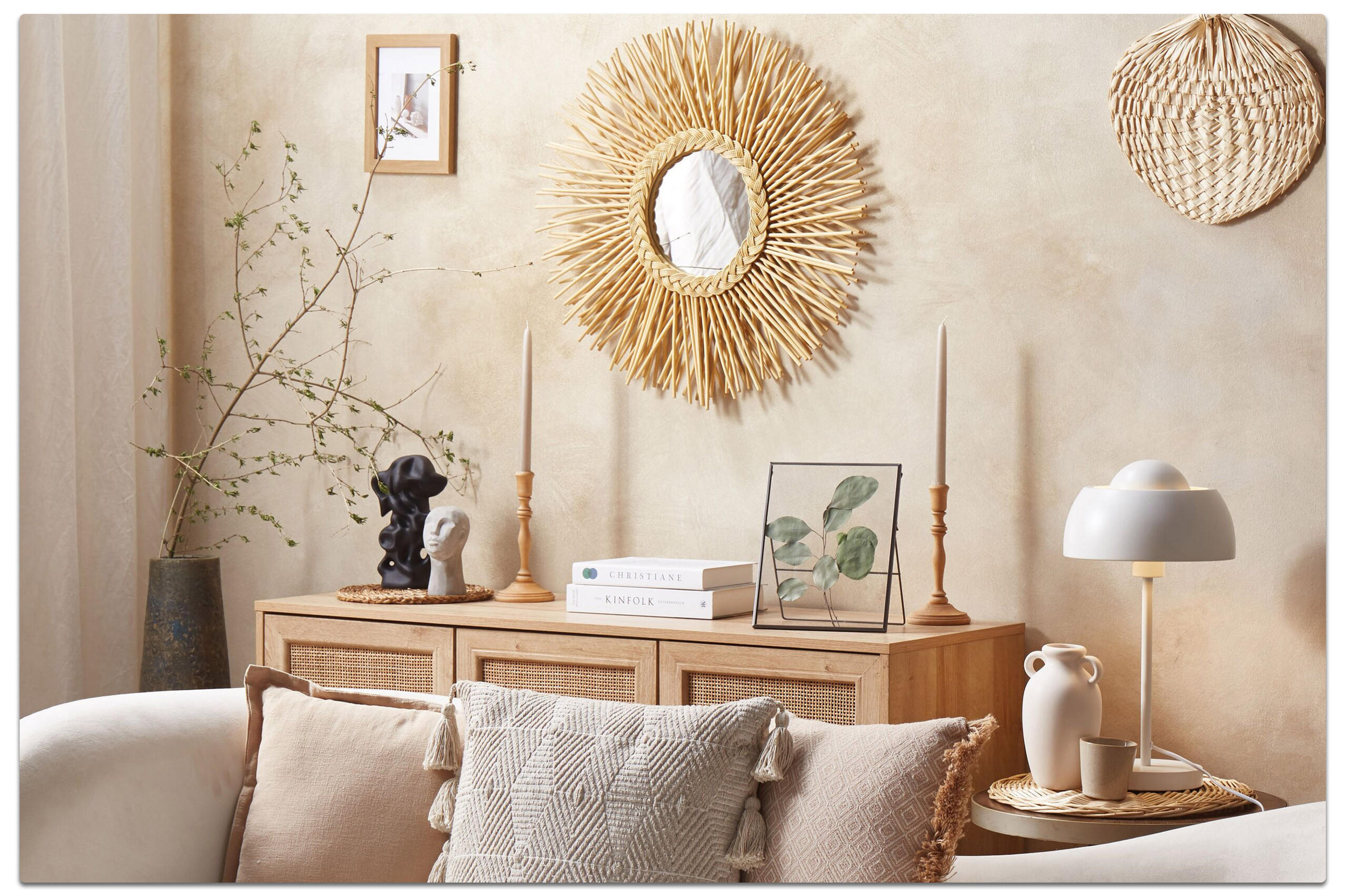 Gemütliche Wohnzimmerecke mit beigem Sofa, Deko auf Sideboard und runder Rattan-Spiegel an der Wand.