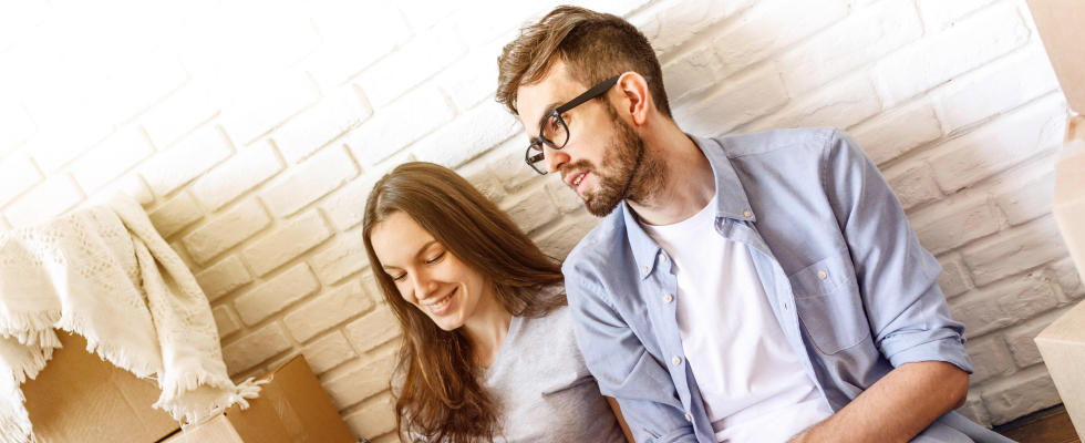 Frau und Mann sitzen an der Wand mit Umzugskartons