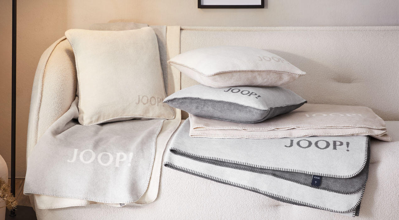 Weiß, grau, beige Wohndecke und Kissen