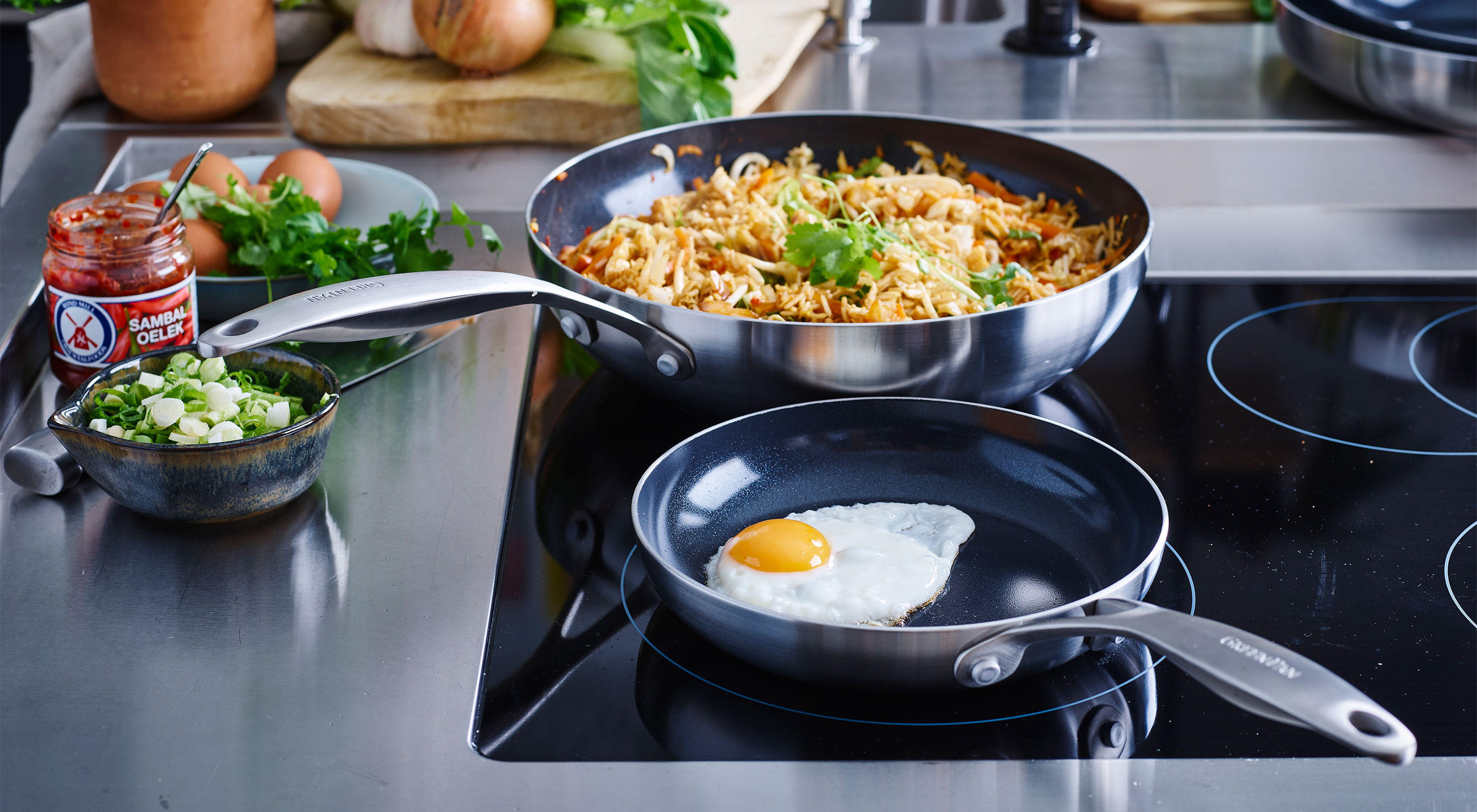 Herdplatte mit zwei Pfannen von GreenPan, eine davon enthält ein brätendes Ei.