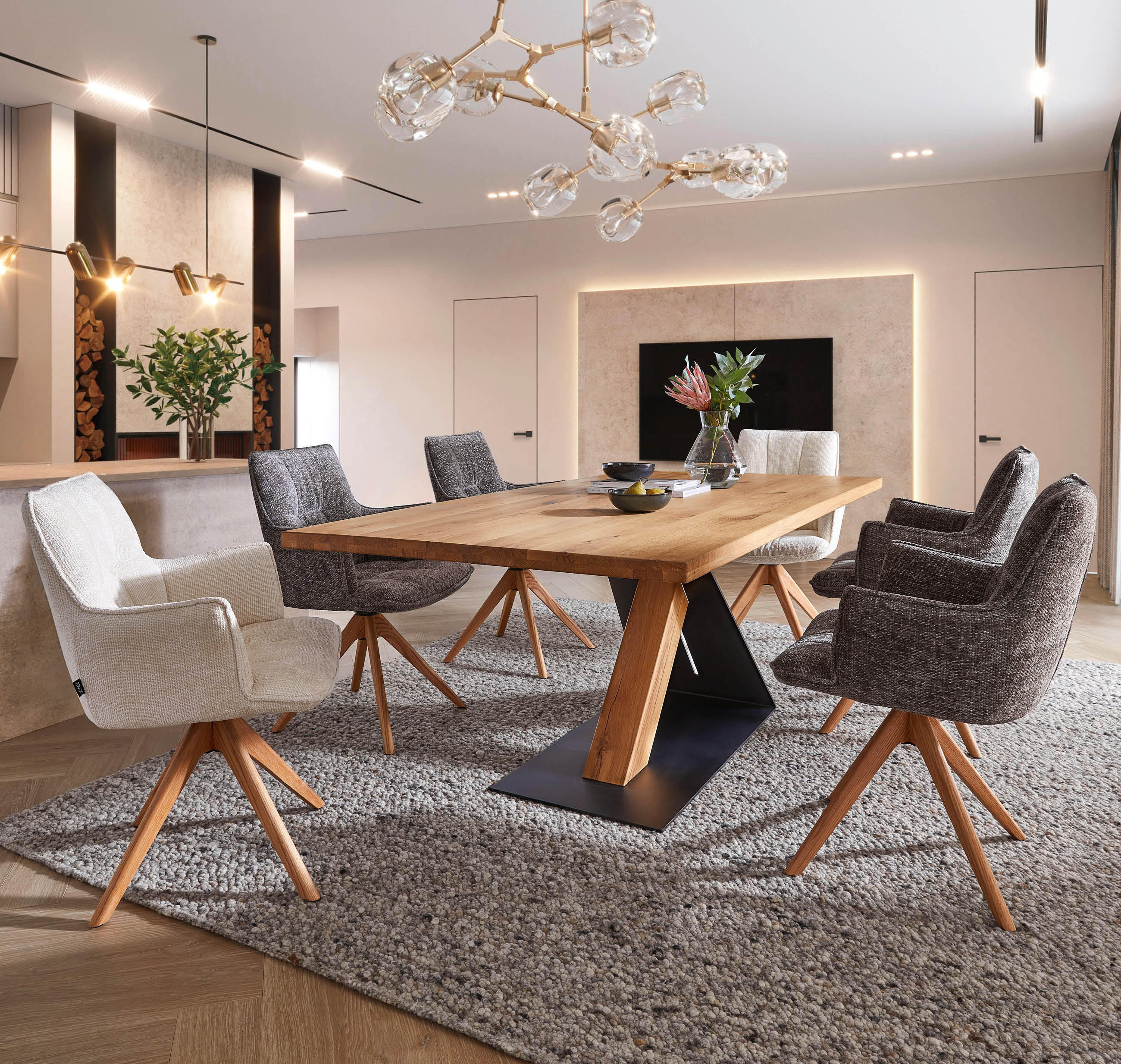 Esszimmertisch aus Holz mit schwarzer Metallbasis umgeben von sechs gepolsterten Stühlen auf grauem Teppich in modernem Raum mit indirekter Wandbeleuchtung