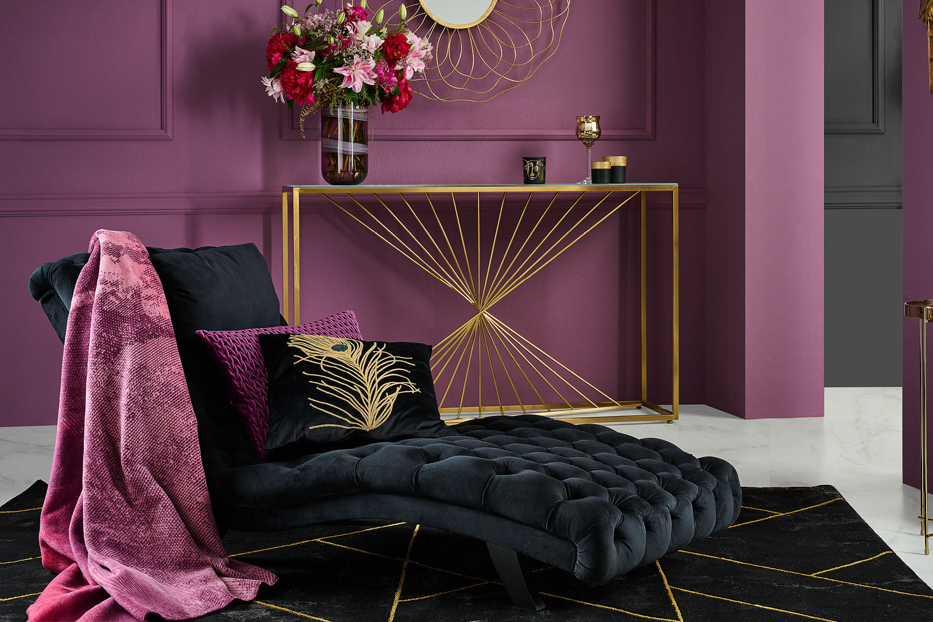 Schwarze Relaxliege auf schwarzem Teppich vor goldenem Highboard