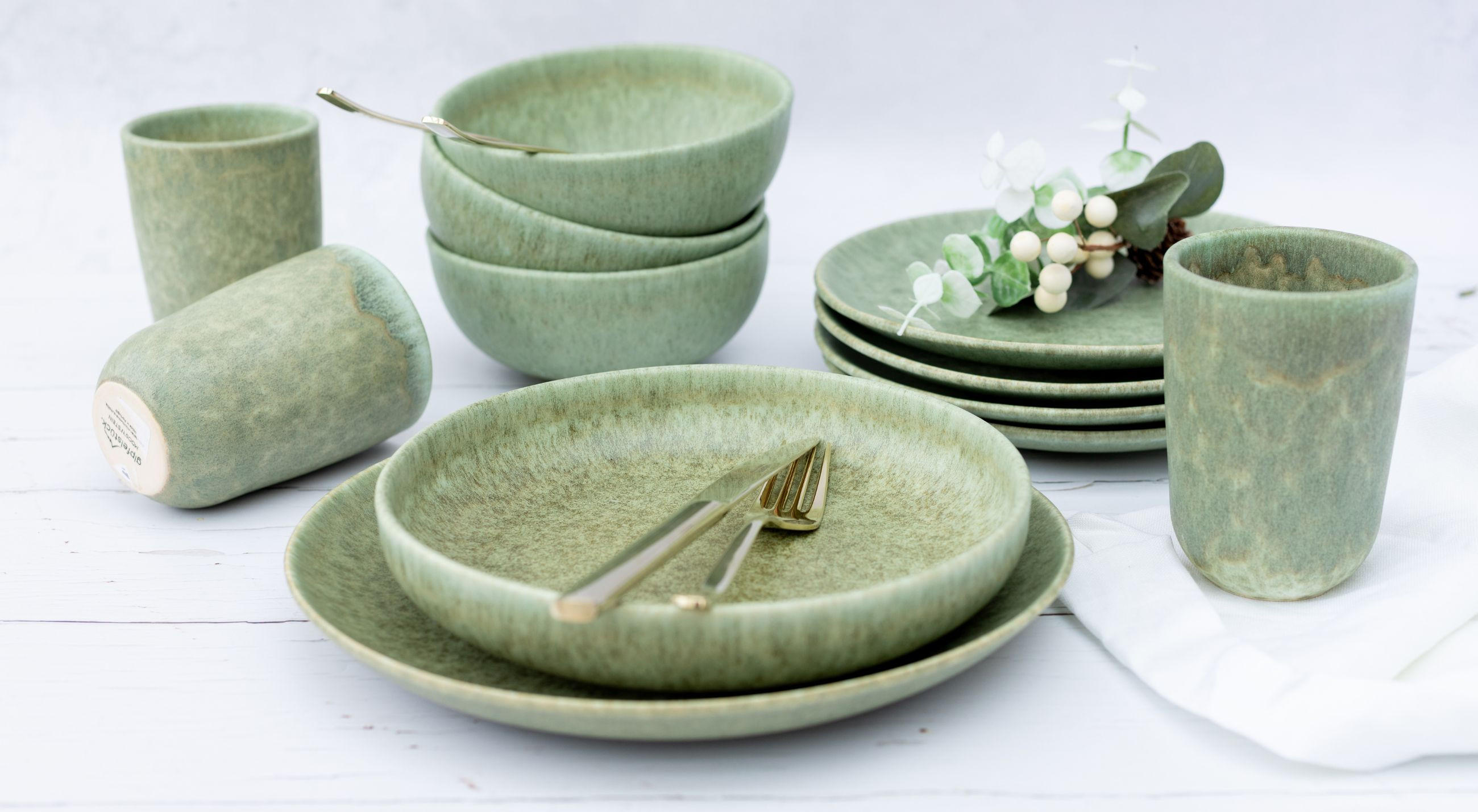 Grünes Kombiservice von GIPFELSTÜCK, das aus verschiedenen Geschirrteilen für stilvolle Mahlzeiten besteht.