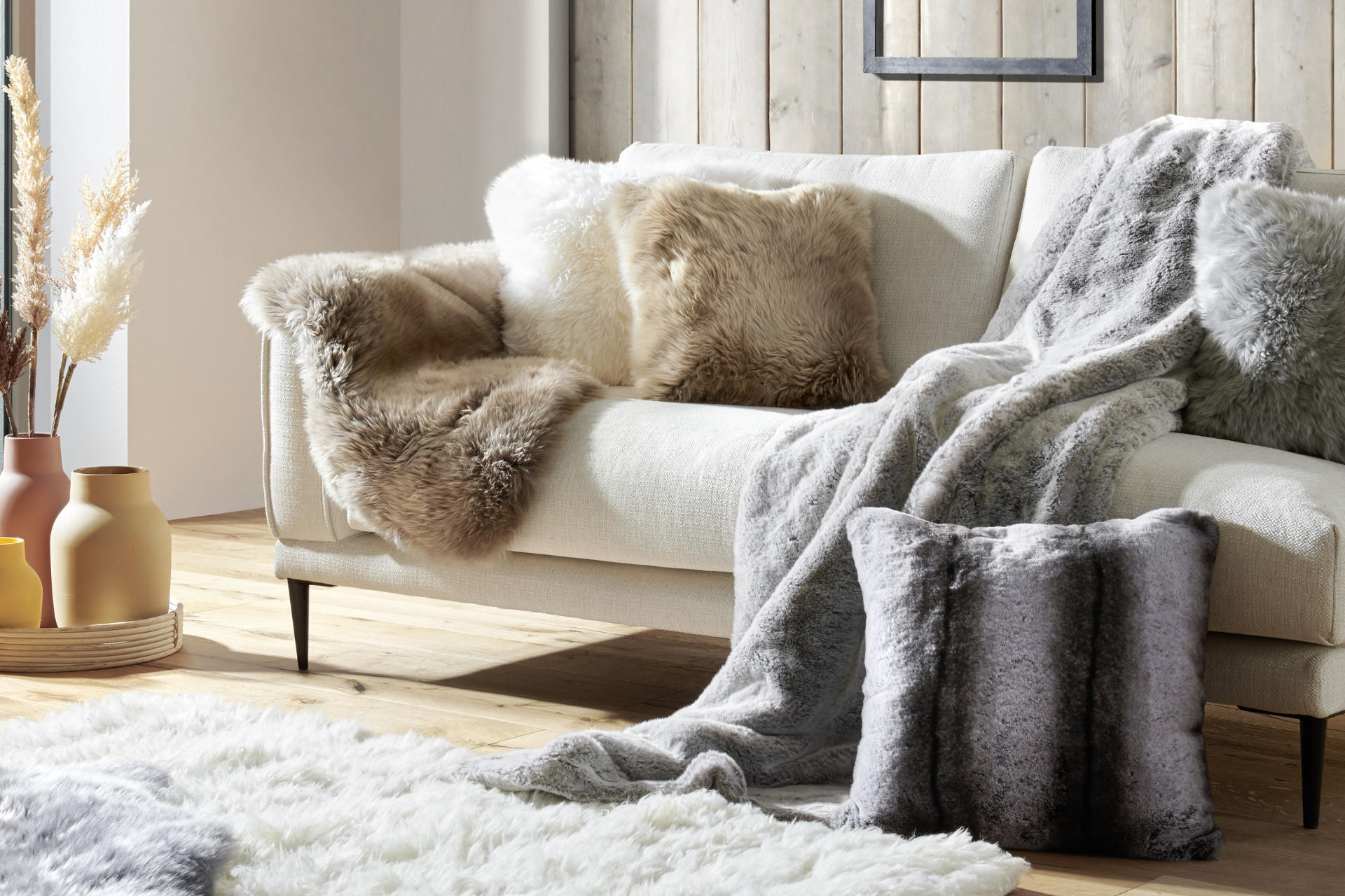 Kuschelige Polster, Decken und Felle auf einem weissen Sofa