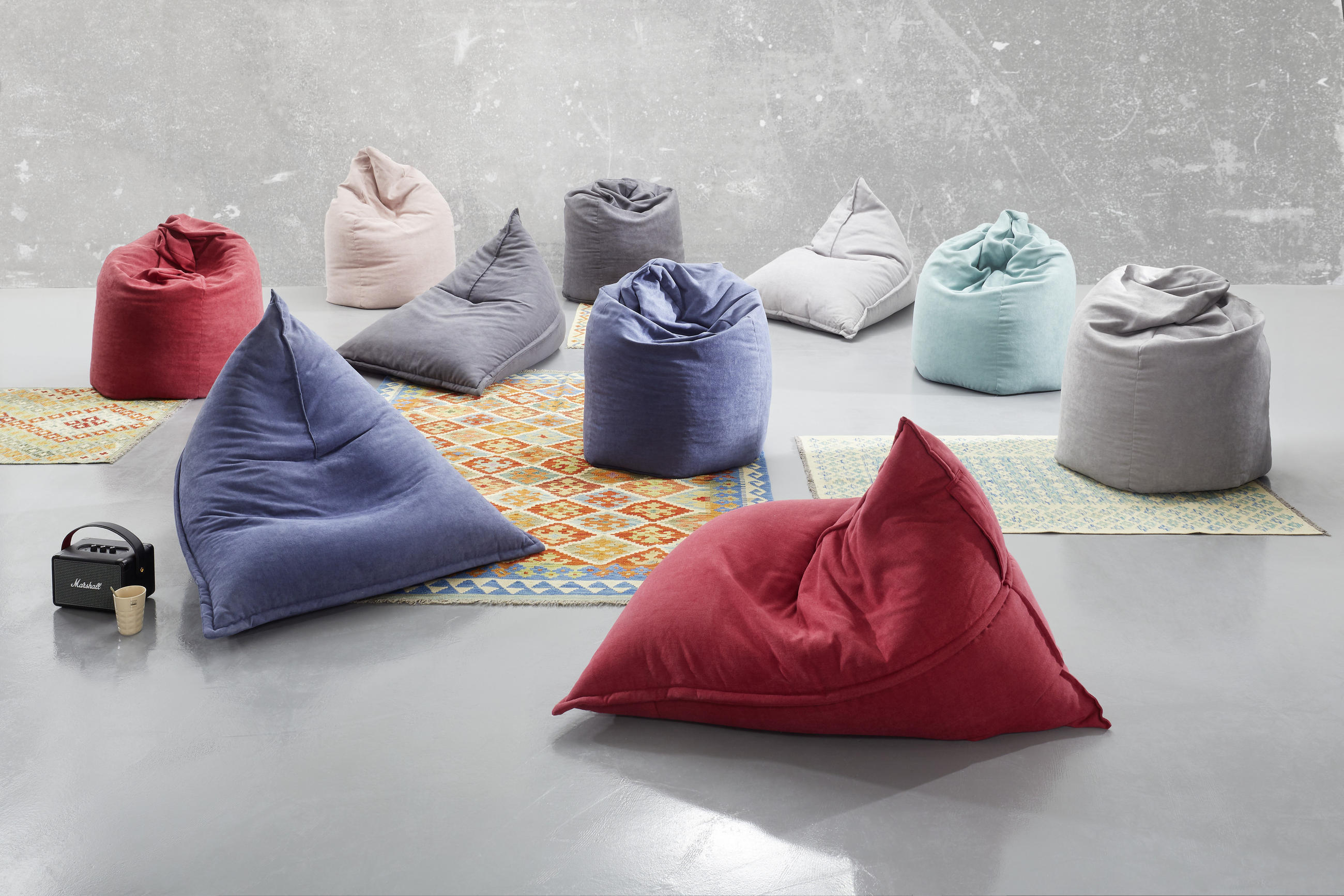 Večbarvnih vreč za sedenje, razporejenih na tleh v prijetnem okolju.