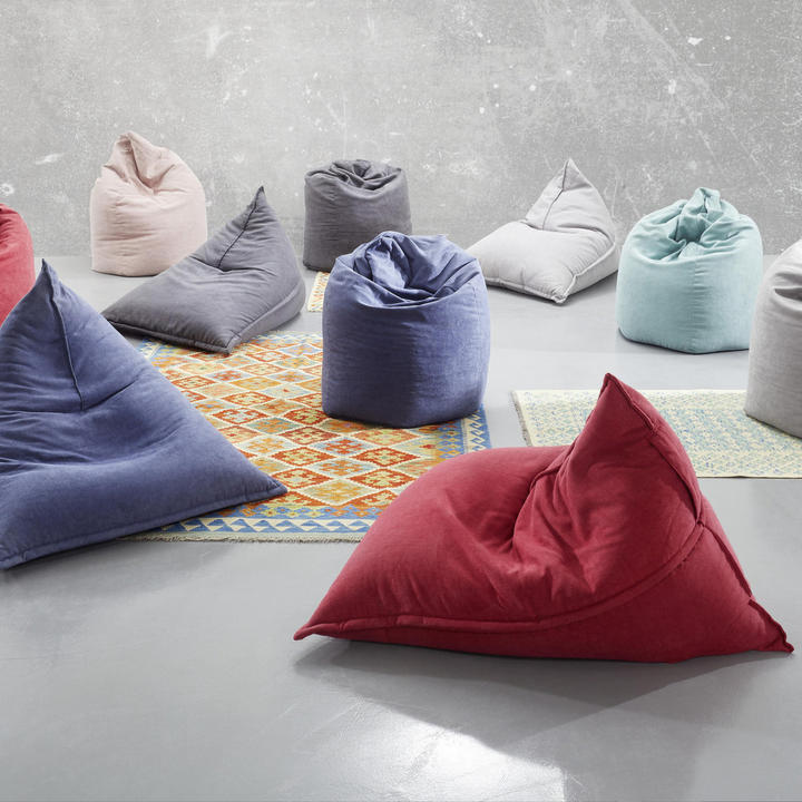 Večbarvnih vreč za sedenje, razporejenih na tleh v prijetnem okolju.