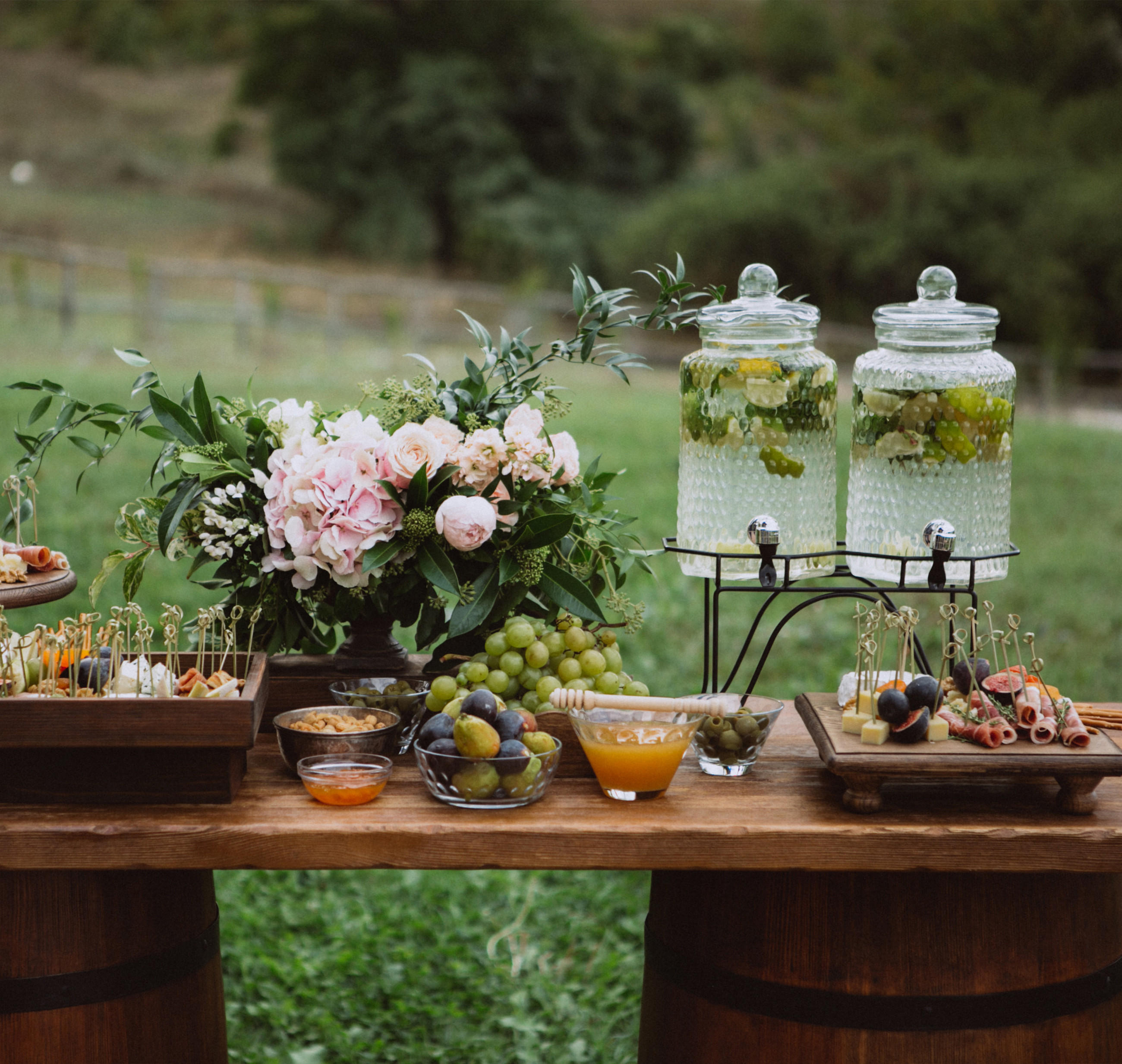 Ein rustikaler Empfangstisch für eine Gartenhochzeit, geschmückt mit Früchten und Blumen.