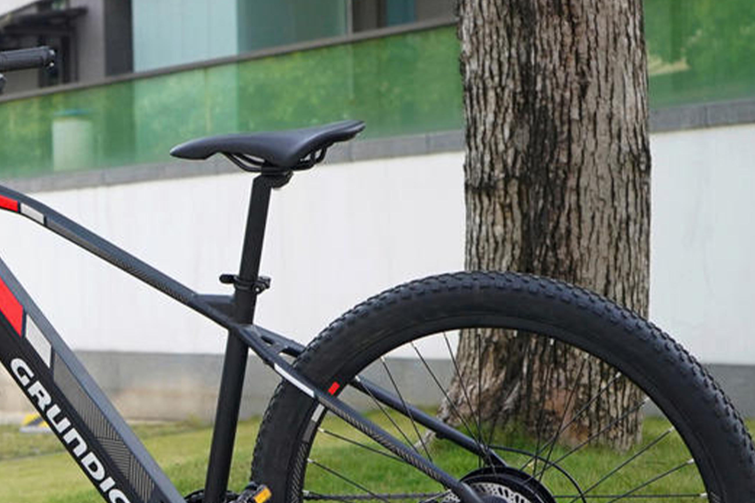 Ein schwarzes E-Bike mit einem Fahrradsattel, geparkt an der Seite eines Gebäudes.