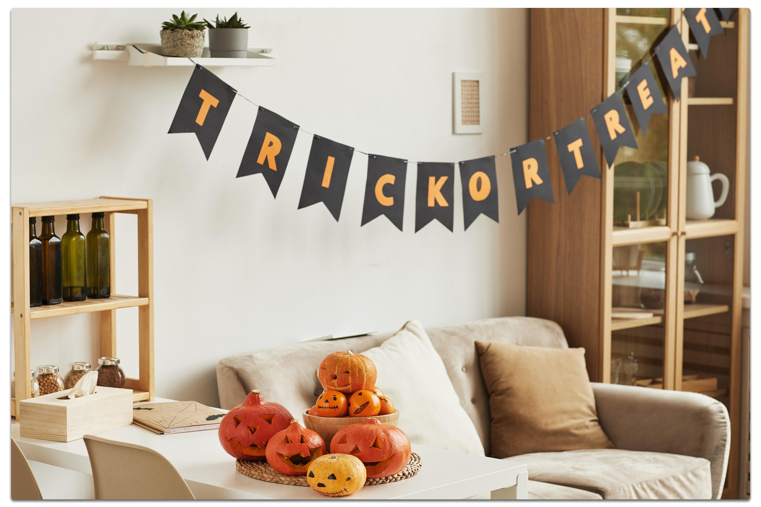 Halloween-Dekoration an der Wand mit einem Kürbis und einem Schild, das "Süßes oder Saures" sagt.