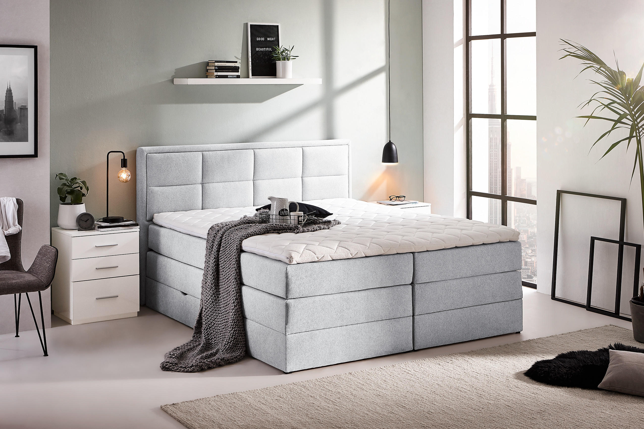 odernes Boxspringbett von Carryhome in hellgrau in einem stilvollen Schlafzimmer mit Nachttisch und Dekoration
