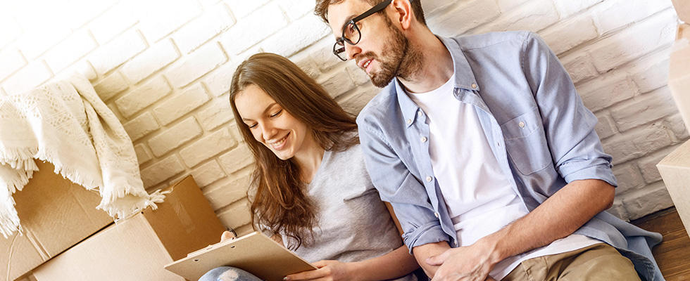 Pärchen sitzt am Boden neben Umzugskartons