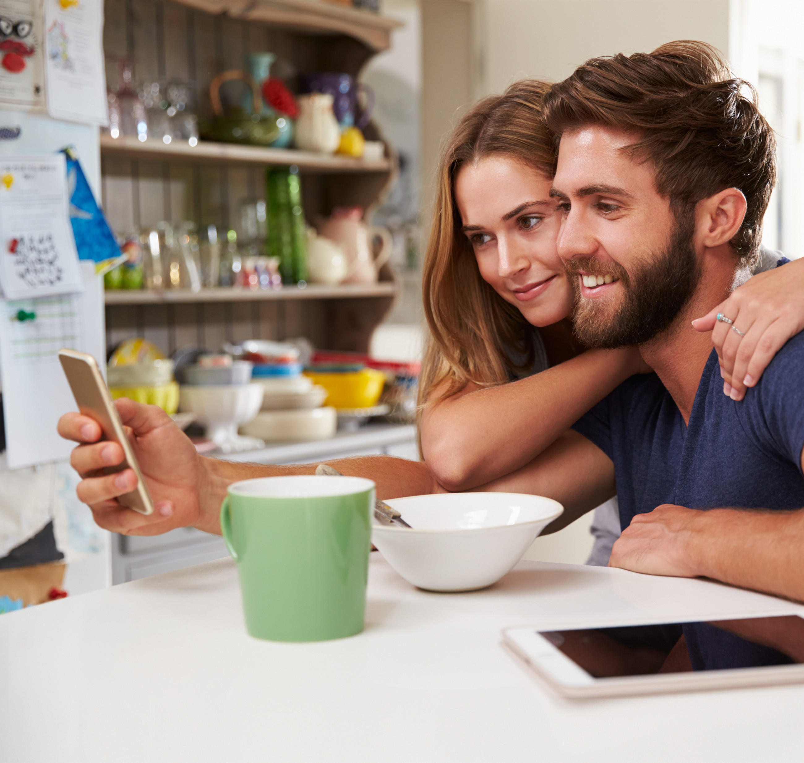 Ein Mann und eine Frau sitzen mit Kaffee und einem Handy am Tisch