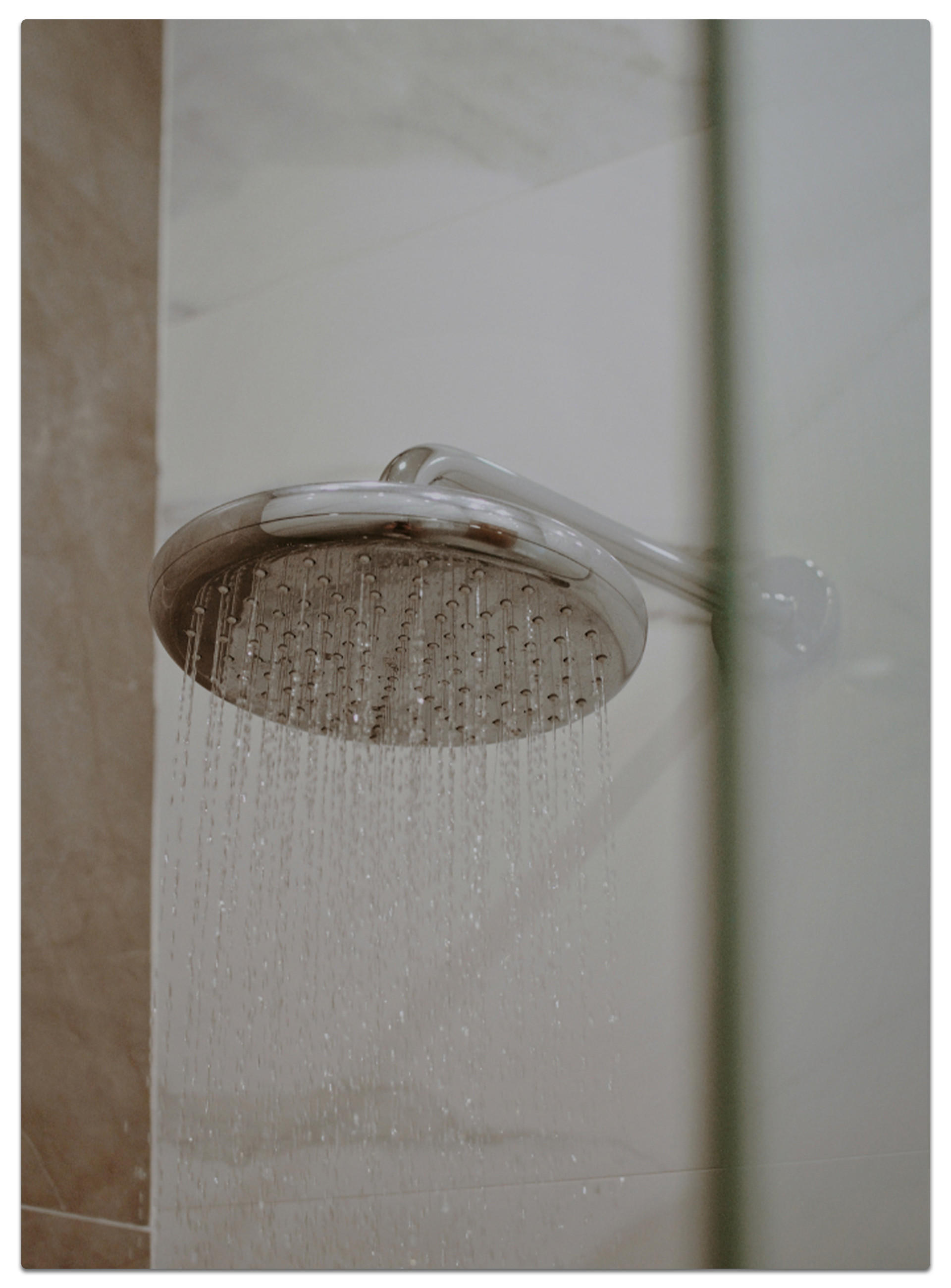 Duschkopf mit fließendem Wasser, das sanft nach unten läuft, in einem modernen Badezimmer.