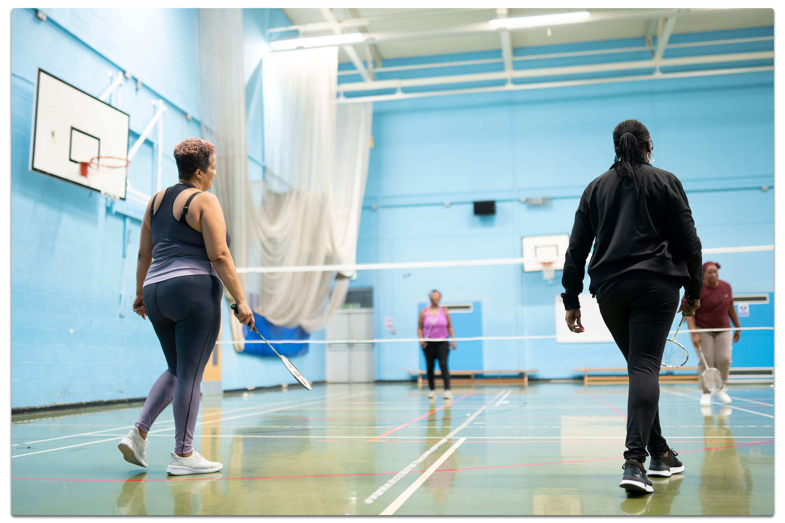 Zwei Frauen spielen Badminton in einer Sporthalle
