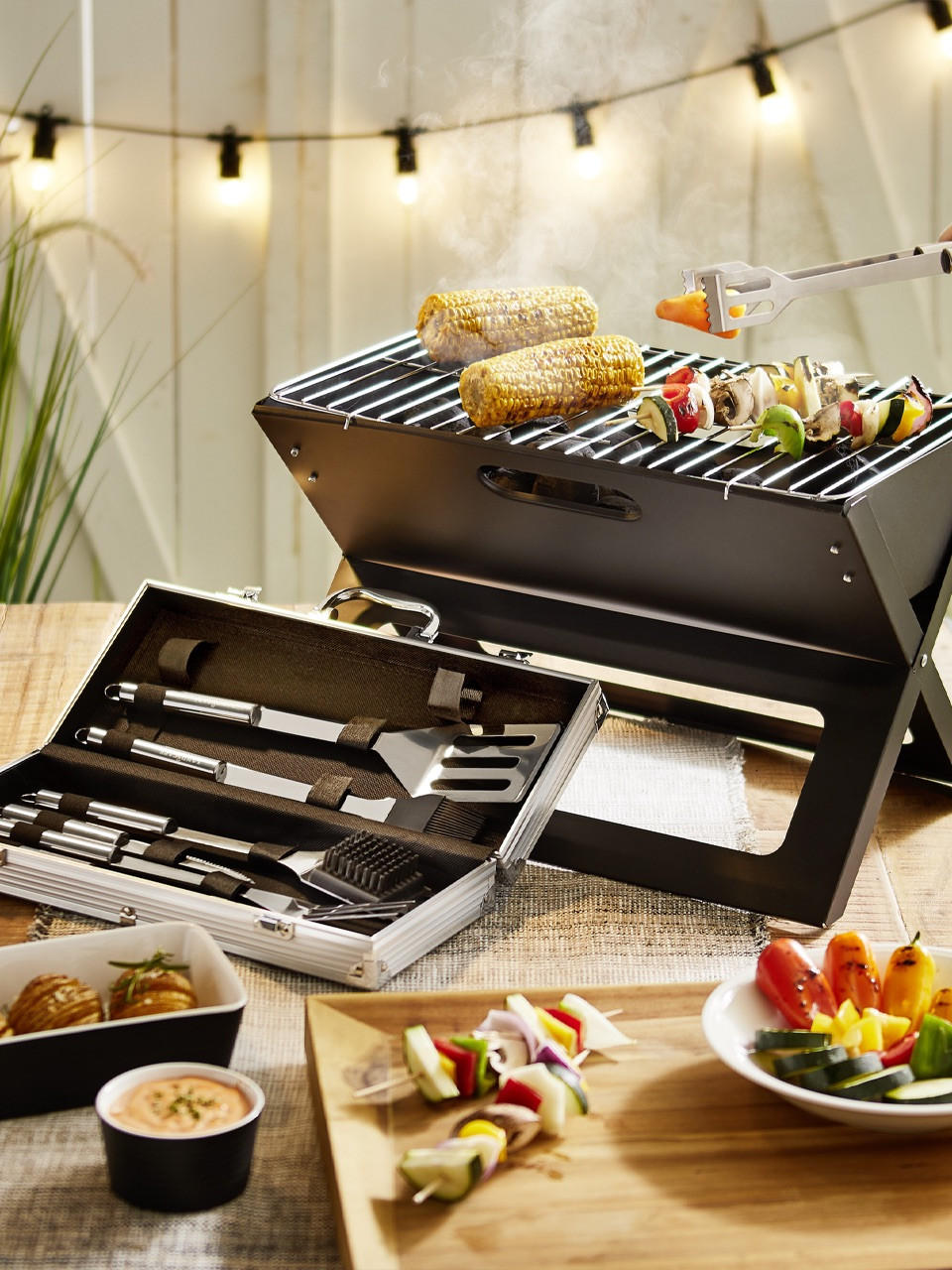 kleiner Grill mit Gemüse und Grillzange als Zubehör