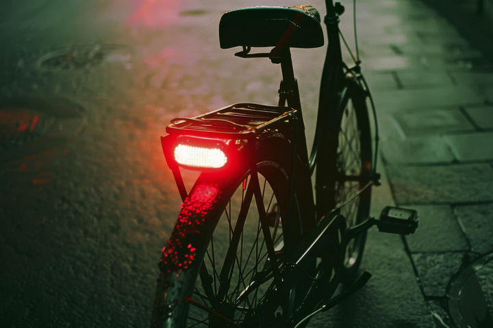 Ein Fahrrad mit einem leuchtend roten Rücklicht, bereit für die Fahrt bei Dämmerung oder Nacht.