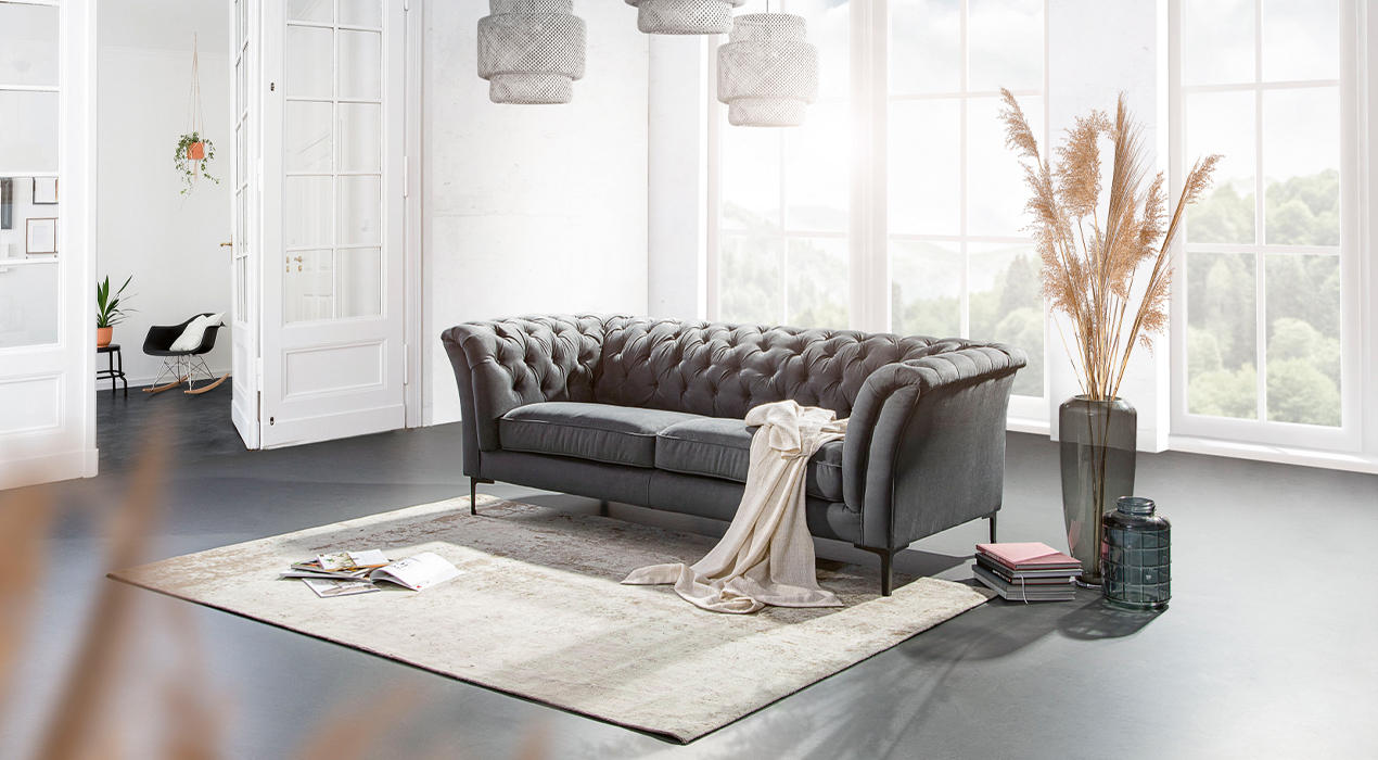 Graues Chesterfield Sofa mit weißer Decke