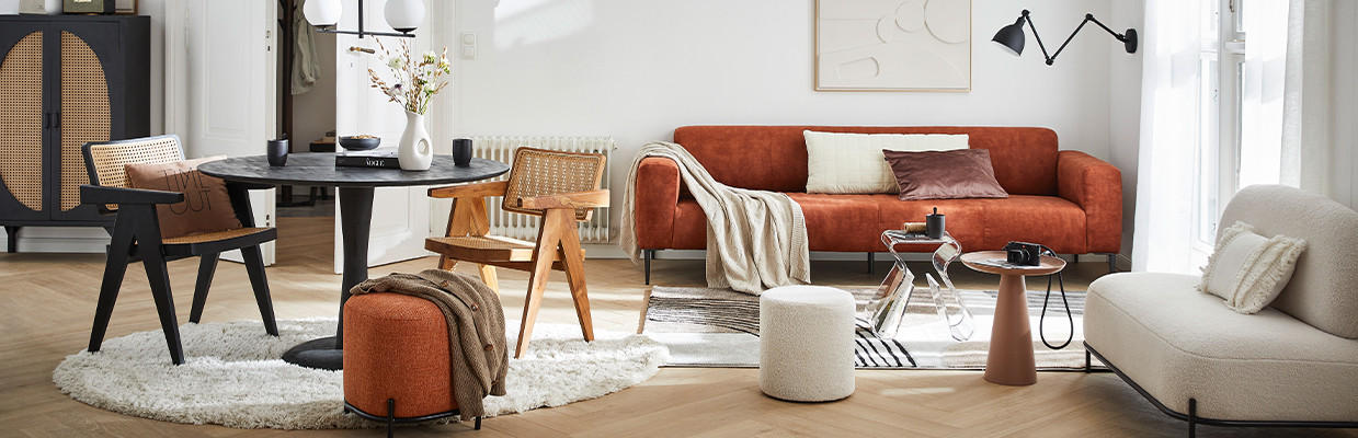 Stilvolles Wohnzimmer mit orangefarbenem Sofa, rundem Esstisch, Designstühlen und dekorativen Akzenten – harmonische Kombination aus modernem und Mid-Century-Stil