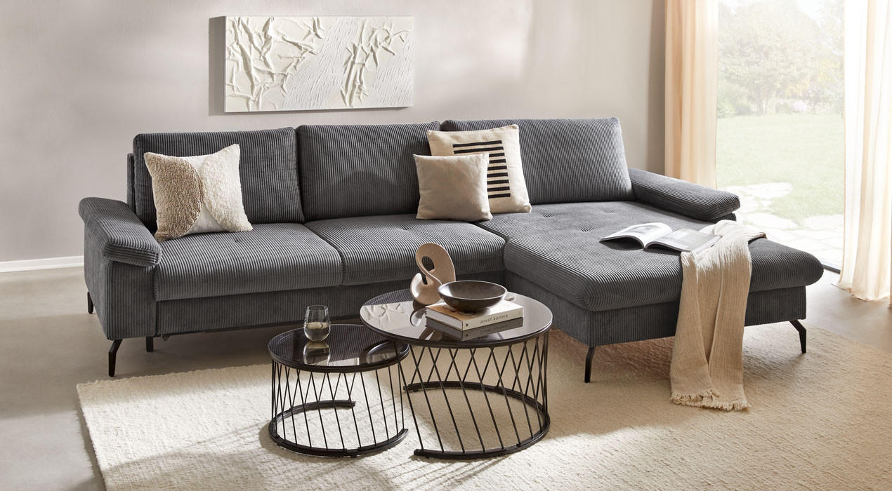 Modernes Wohnzimmer mit grauem Sofa, Couchtischen und Wandkunst.