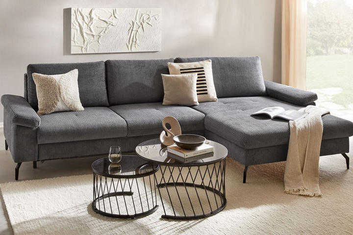 Modernes Wohnzimmer mit grauem Sofa, Couchtischen und Wandkunst.