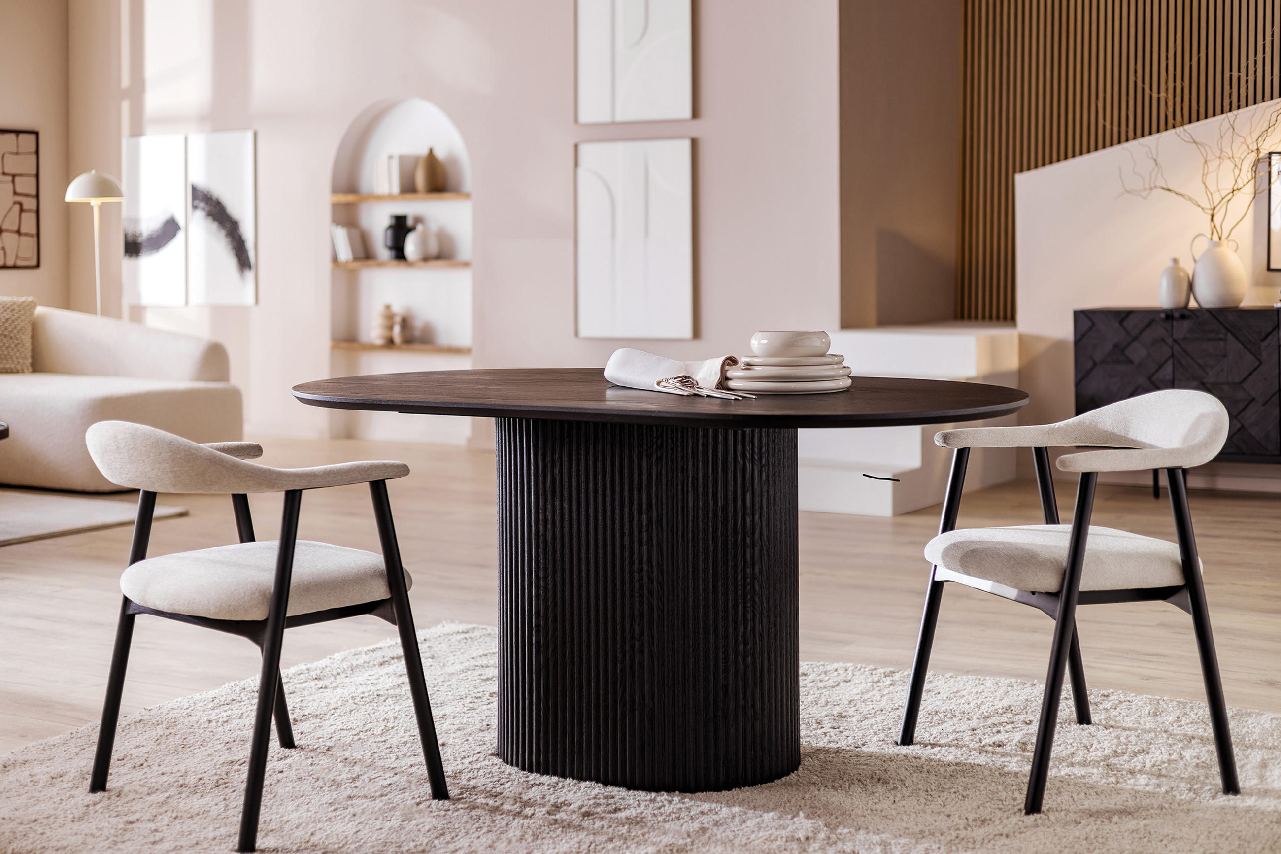 Eleganter runder Esstisch aus dunklem Holz mit zwei modernen Polsterstühlen in hellem Stoff in stilvollem Wohnzimmer.