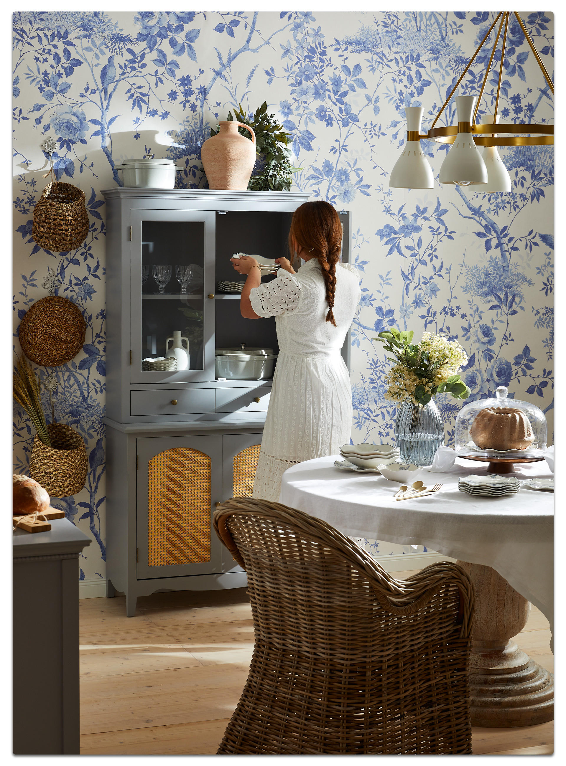 Eine Frau steht vor einem Schrank im Country-Cottage-Stil, umgeben von einer einladenden Osterbrunch-Atmosphäre.