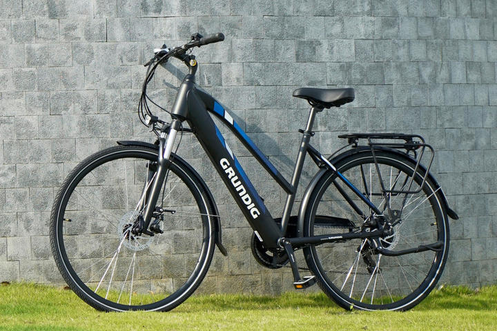 Ein schwarzes und blaues E-Bike lehnt an einer Wand, ideal für die Pflege und um seinen Glanz zu zeigen.