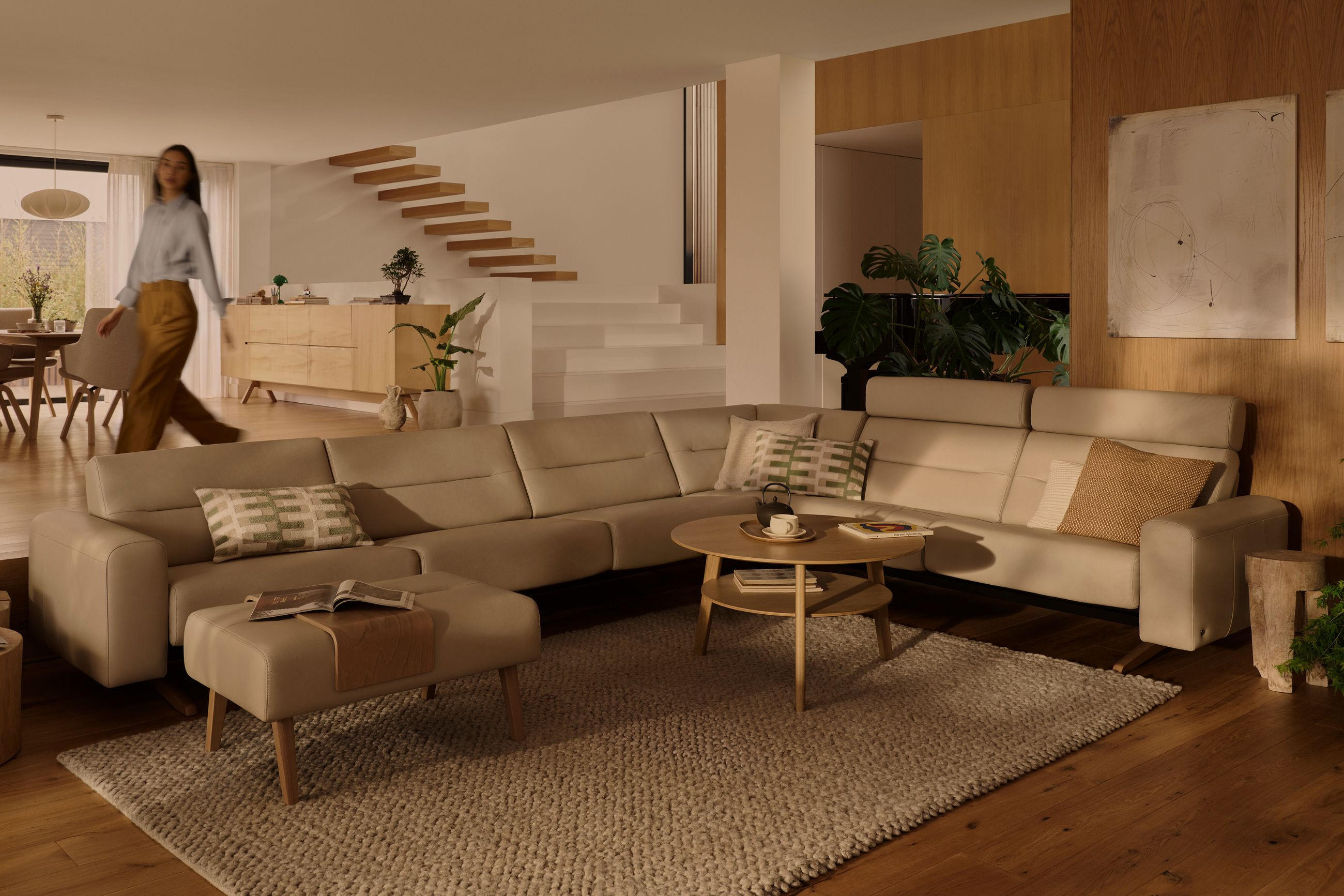 Beigefarbene Wohnlandschaft von STRESSLESS mit Beistelltisch und Hocker, einem stilvoll eingerichteten Wohnzimmer.