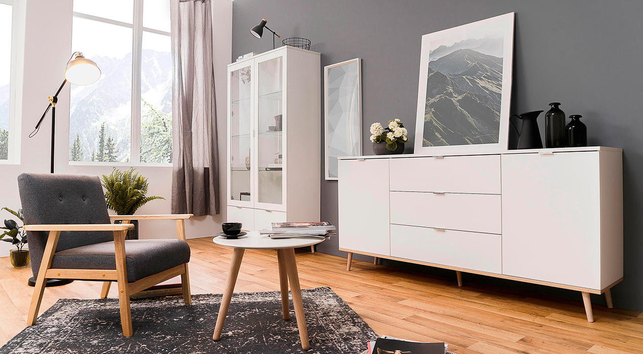 Weiße Wohnwand im Skandi-Look mit hellen Holzfüßen.