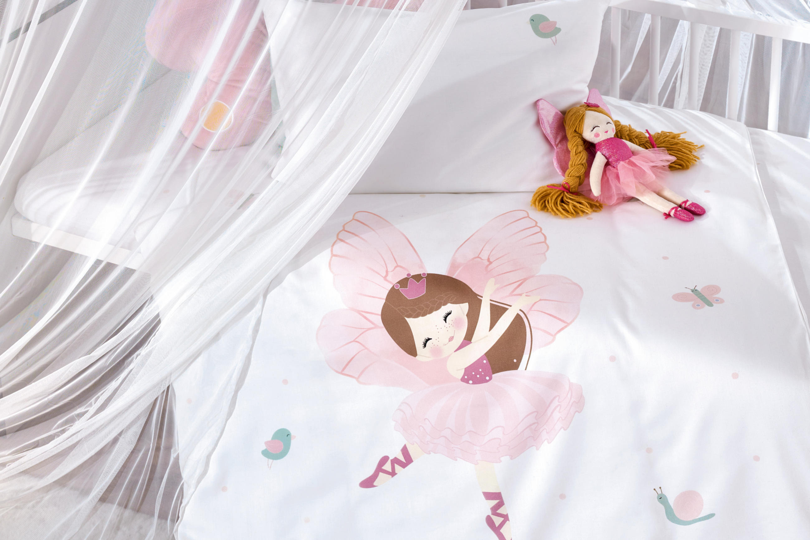 Weißes Babybett mit rosaweißer Bettwäsche